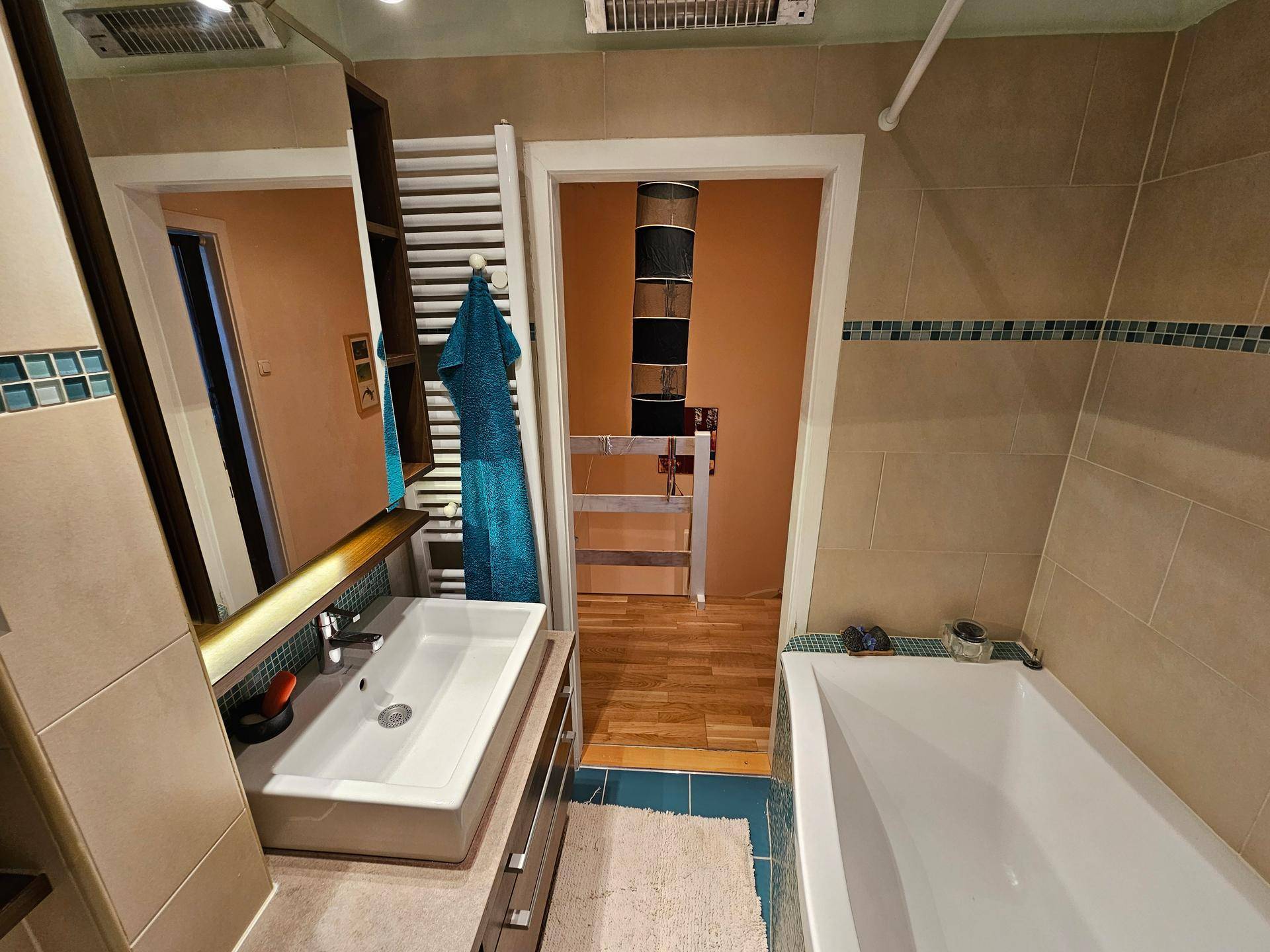 Badezimmer mit modernem Waschbecken, Spiegelschrank und beheiztem Handtuchhalter.