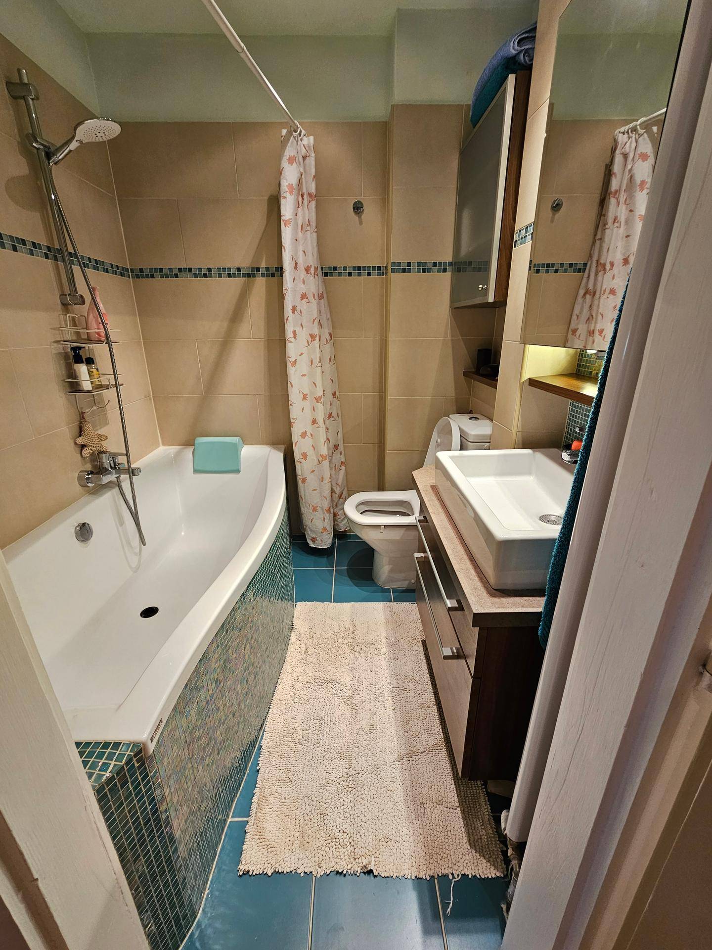 Badezimmer mit Badewanne, Dusche, Waschbecken und WC, gefliesten Wänden und Boden.