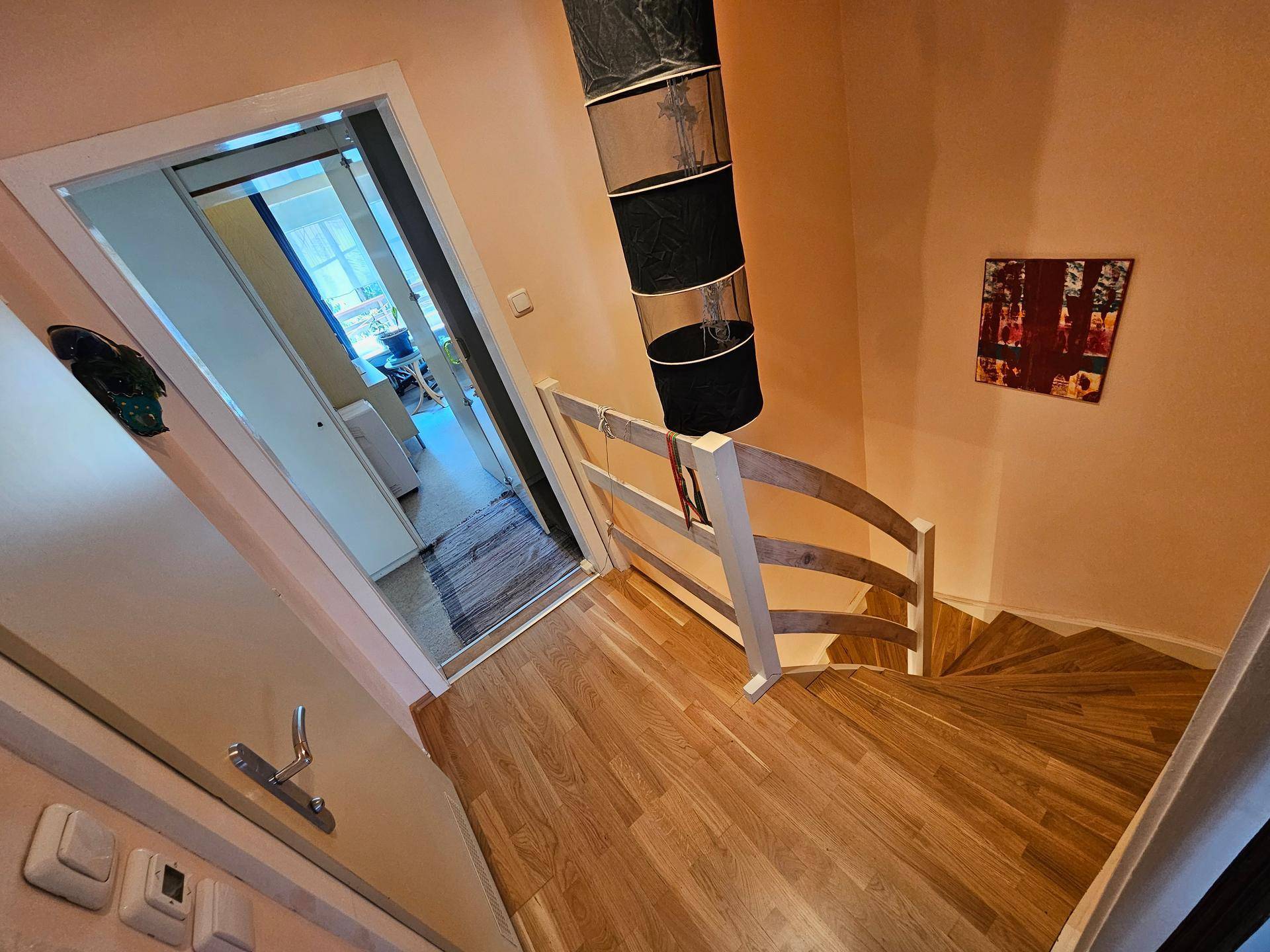 Holztreppe mit Geländer, die zu den oberen Etagen des Hauses führt.