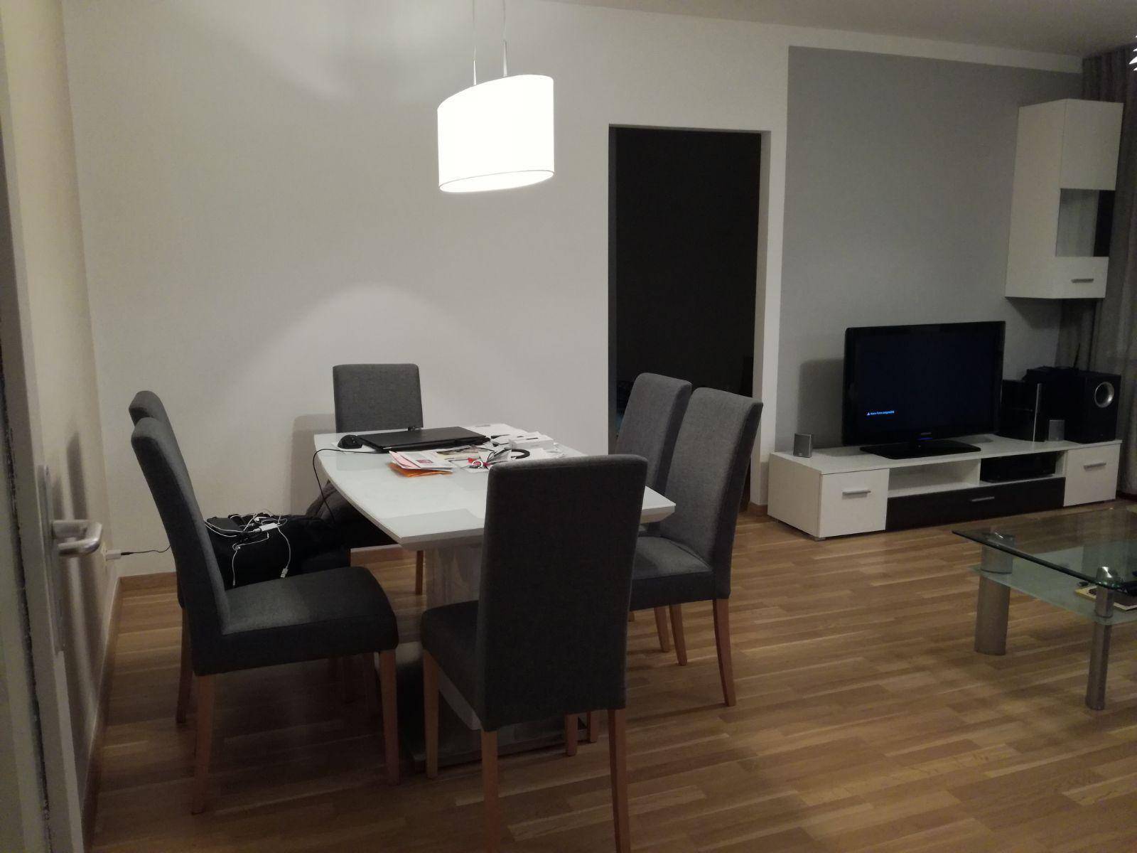 Essbereich mit modernem Tisch und Stühlen, angrenzend an den Wohnbereich mit Fernseher.