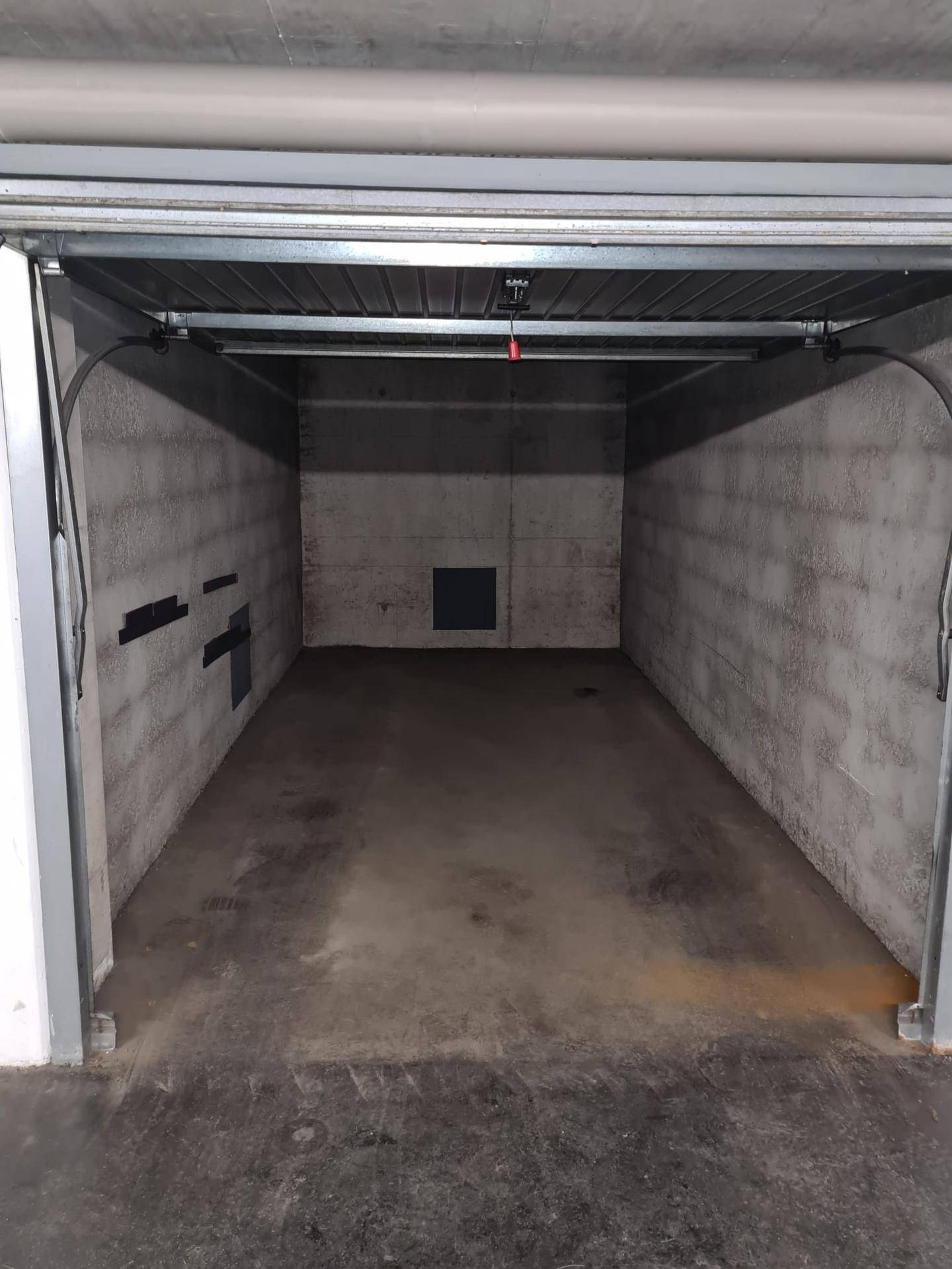 Leere, offene Garagenbox mit Betonwänden und -boden in einer Tiefgarage, bereit zur Nutzung.