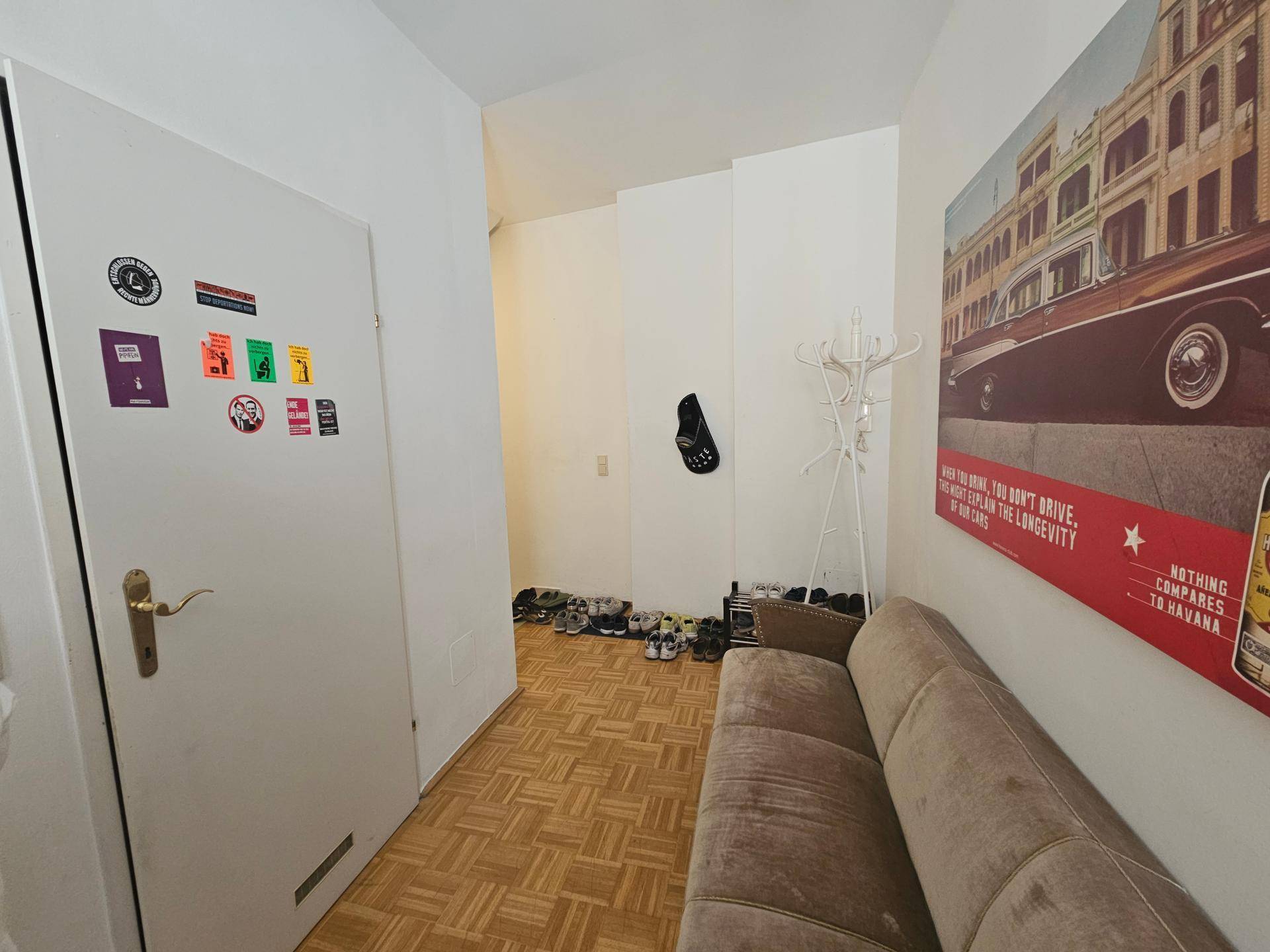 Eingangsbereich mit Sitzgelegenheit, Schuhablage und einem großen Wandbild.
