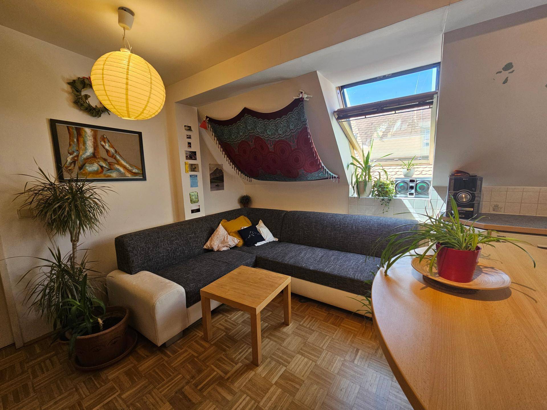 Gemütlicher Wohnbereich mit Ecksofa, Holztisch und Blick auf die angrenzende Küche.