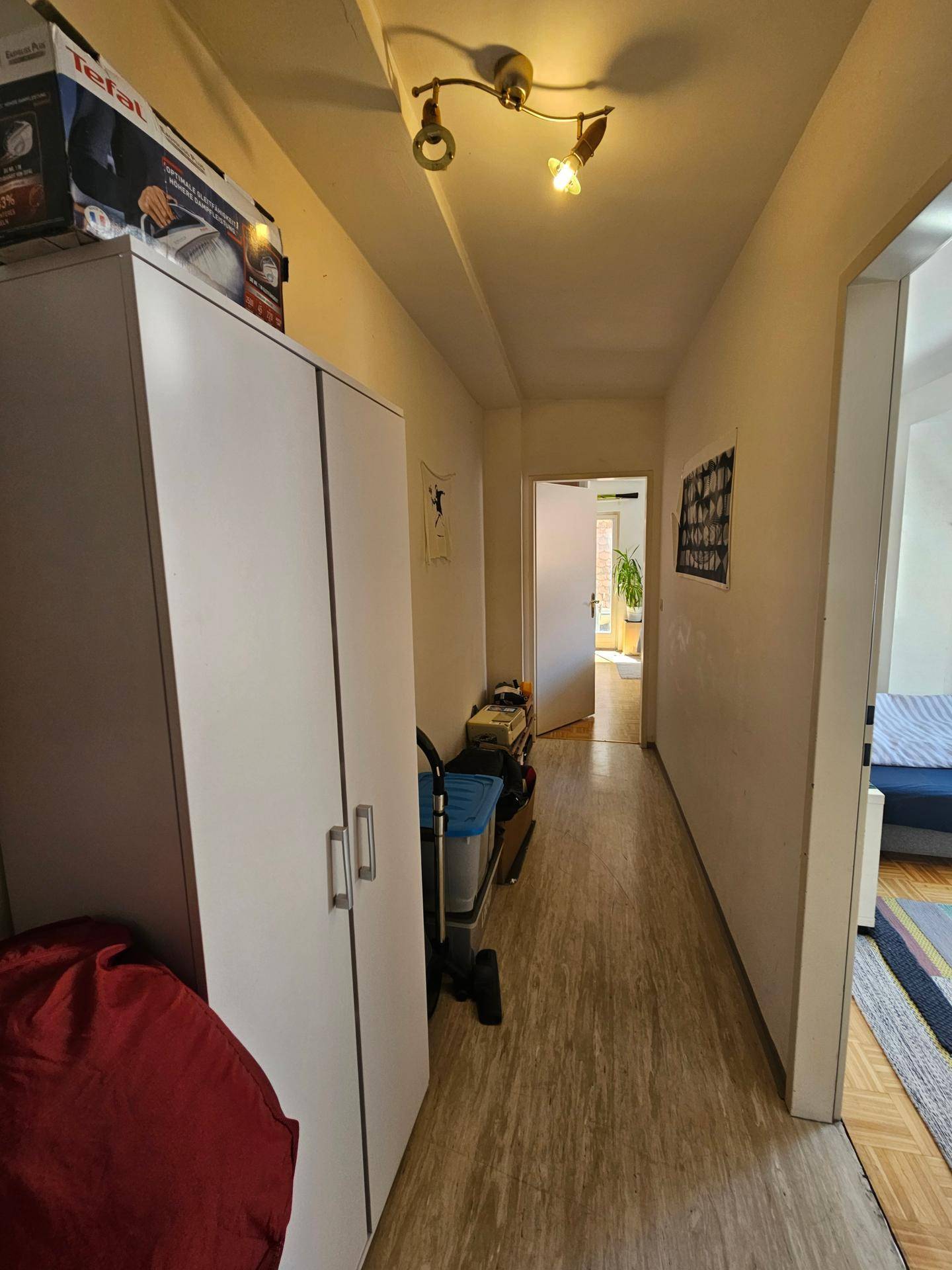 Langer Flur mit weißem Schrank und Blick in angrenzende Räume.
