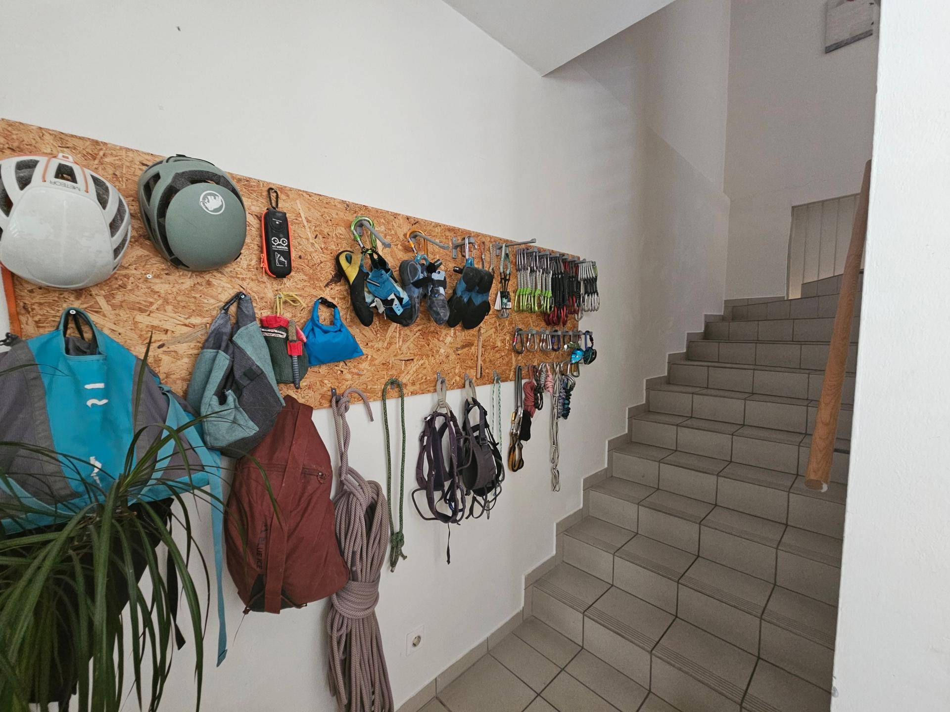 Treppenhaus mit gefliesten Stufen und einer Wanddekoration aus Kletterausrüstung.