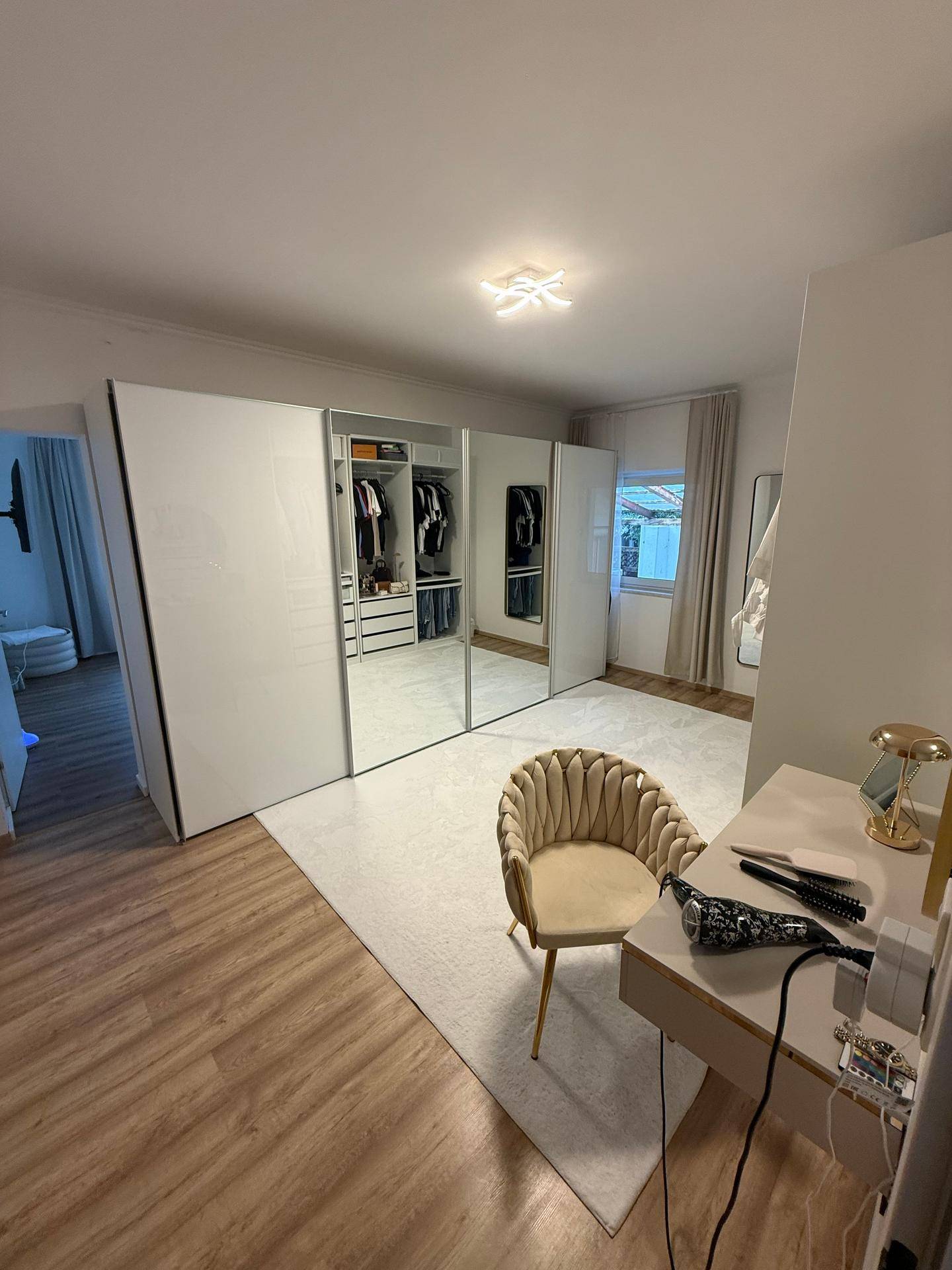 Modernes Ankleidezimmer mit großen Spiegelschränken, Schminktisch und Teppichbereich.