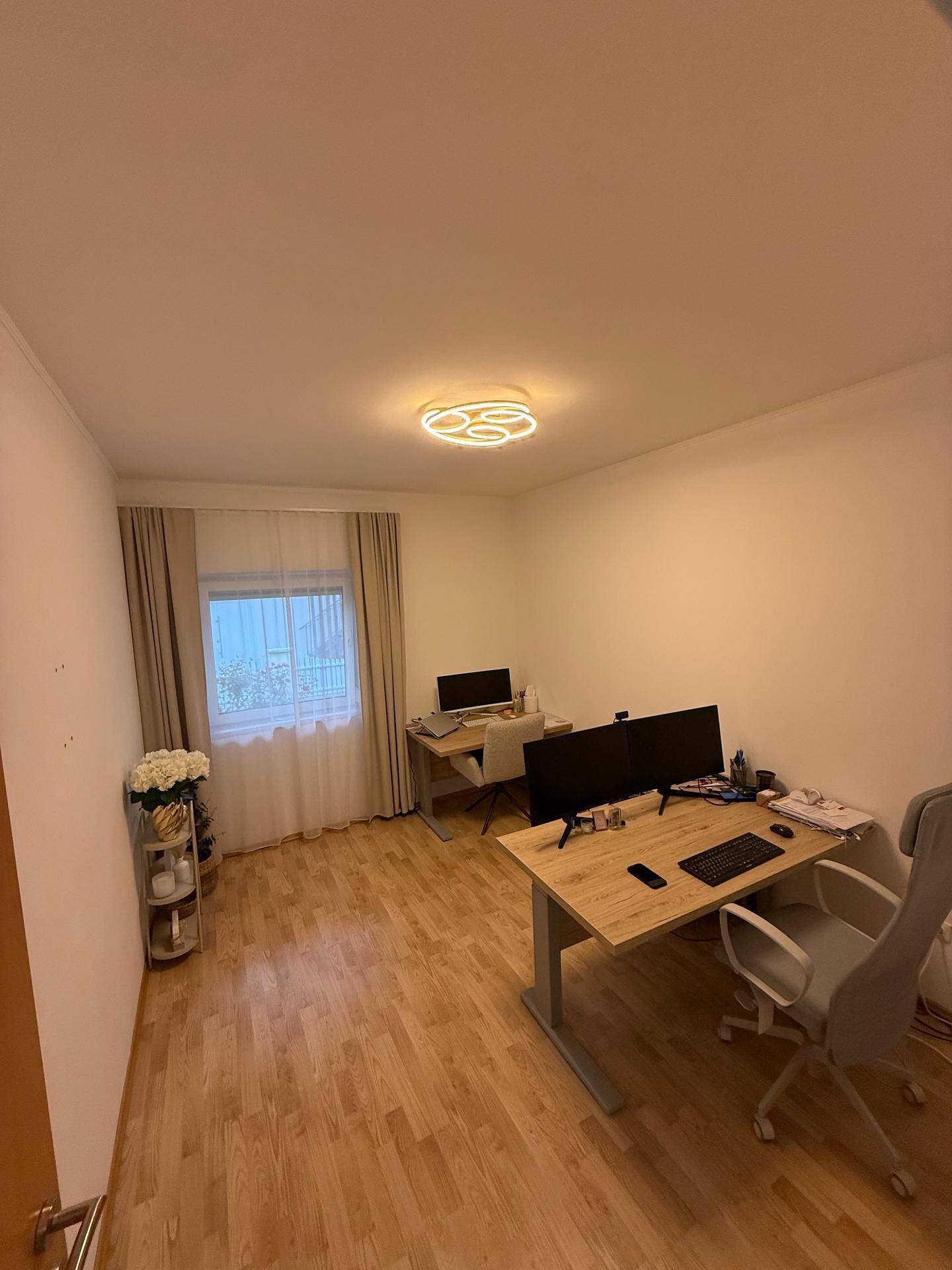 Helles Arbeitszimmer mit zwei Schreibtischen, Bürostühlen und Holzboden.