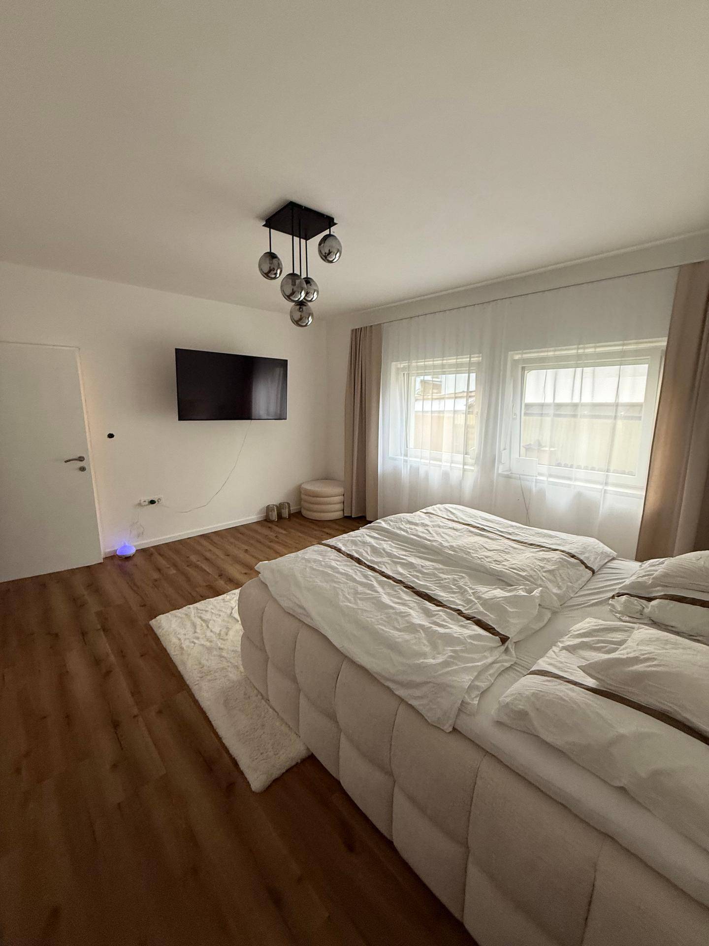 Modern eingerichtetes Schlafzimmer mit bequemen Bett und Wandfernseher.