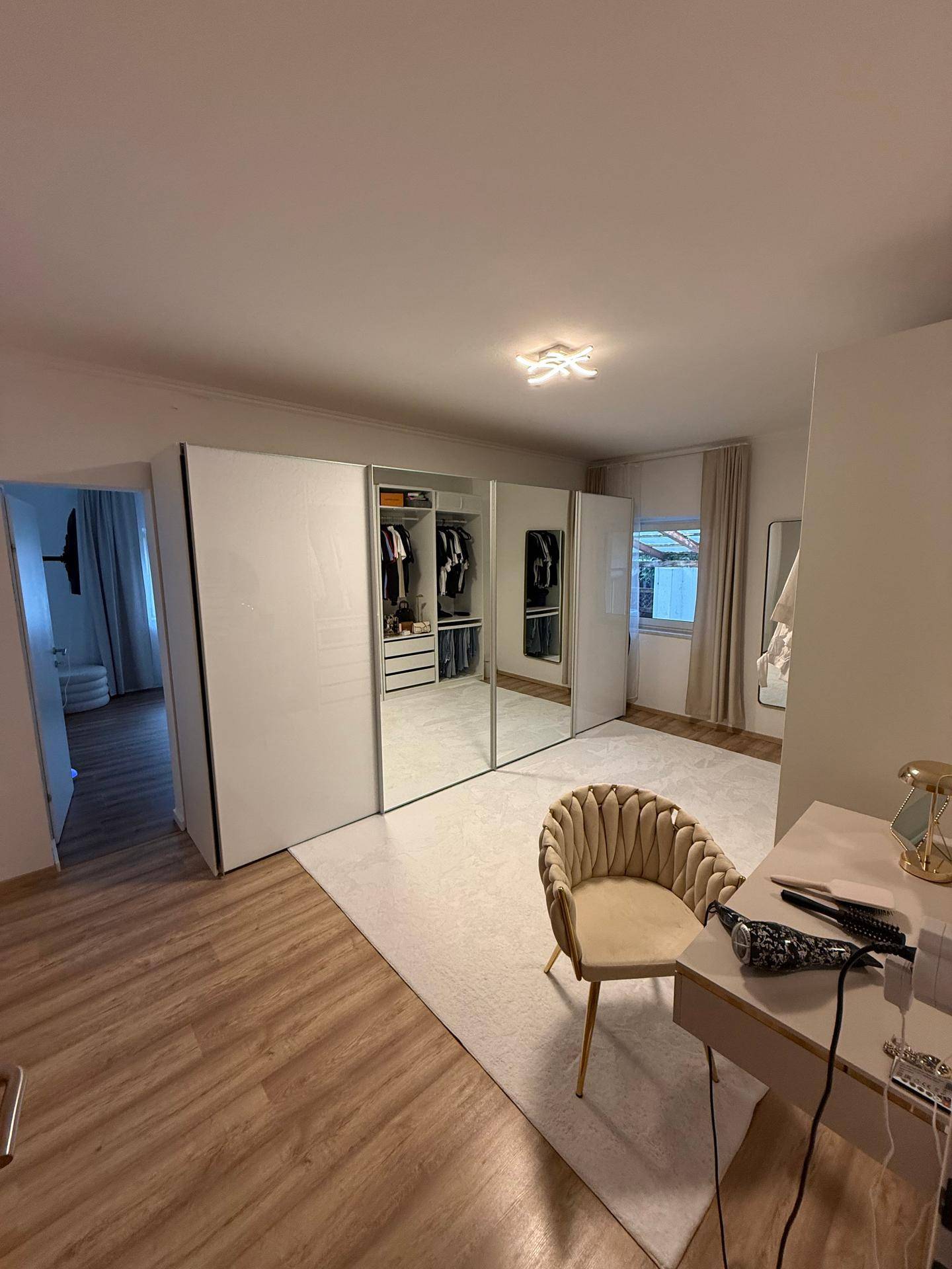 Elegantes Ankleidezimmer mit Spiegelschränken, Schminktisch und Holzboden.