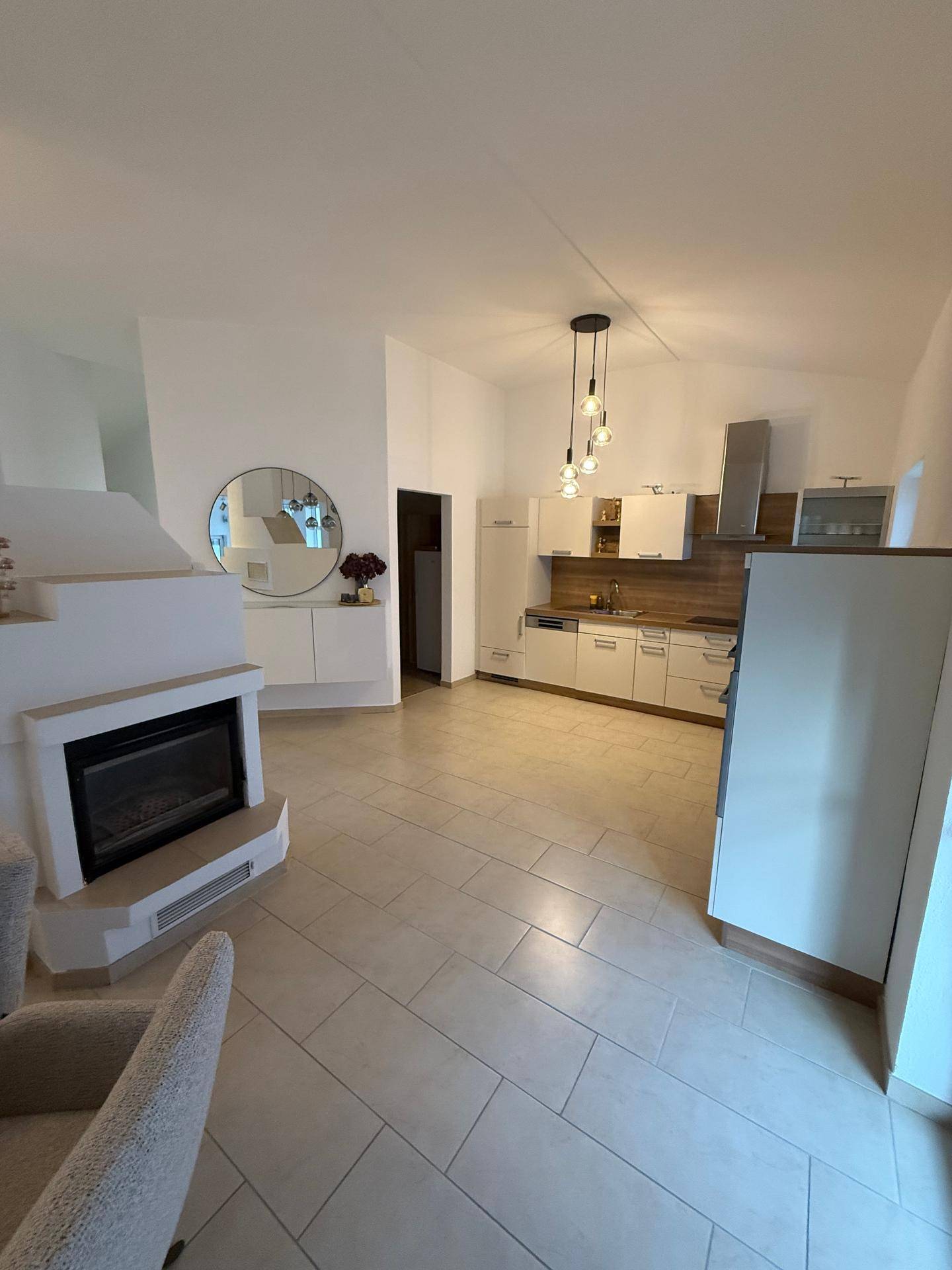 Moderne Küche mit weißen Schränken, Kamin und hellen Fliesenböden.