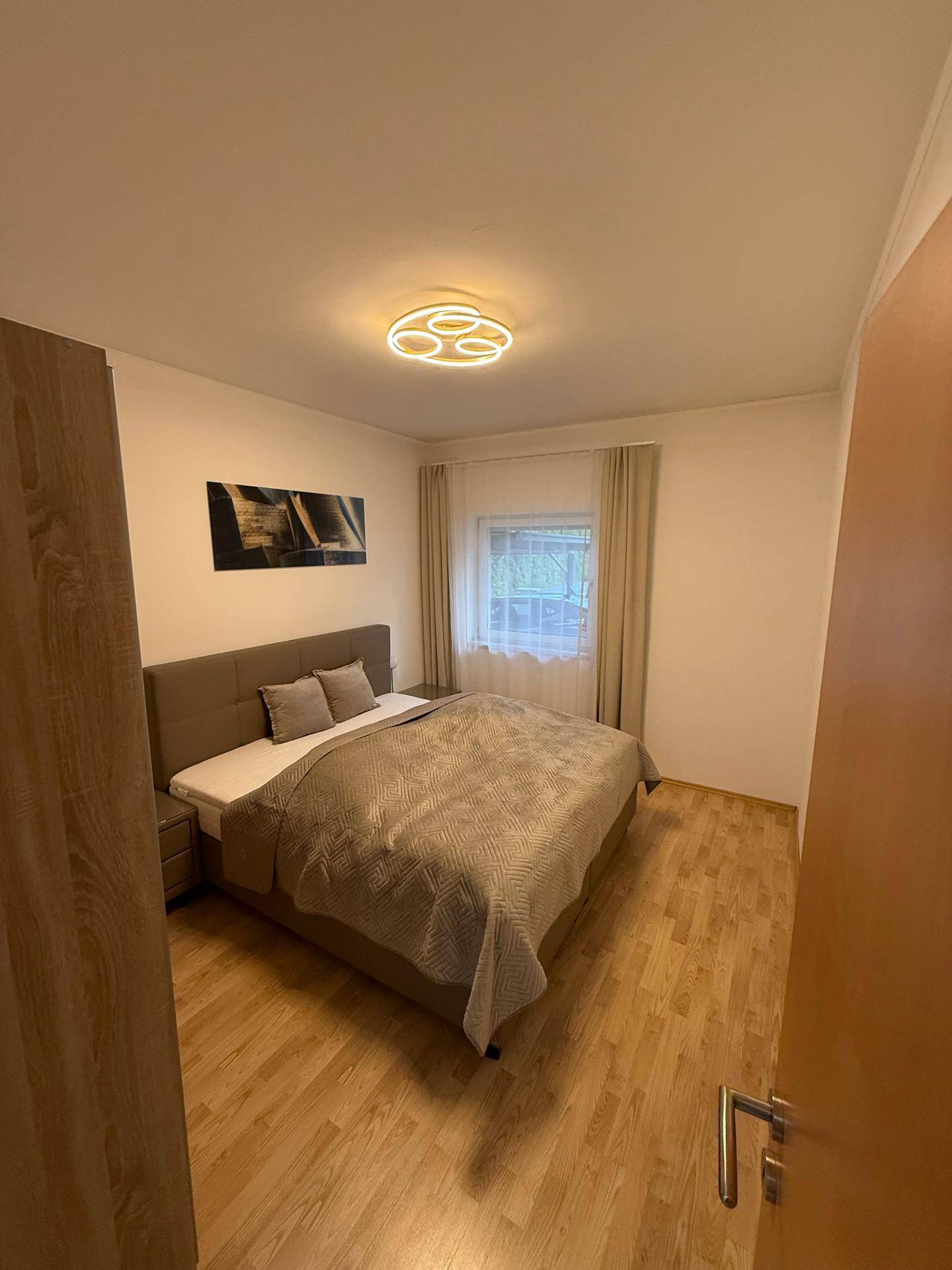 Gemütliches Schlafzimmer mit Doppelbett, Holzboden und Fenster für natürliches Licht.
