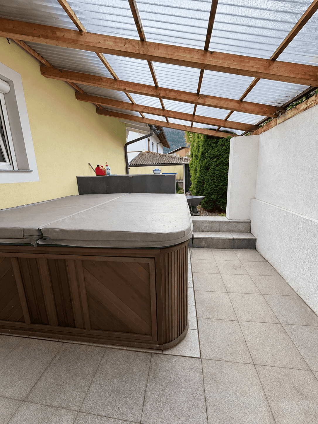 Überdachte Terrasse mit Whirlpool und Fliesenboden, ideal zum Entspannen im Freien.