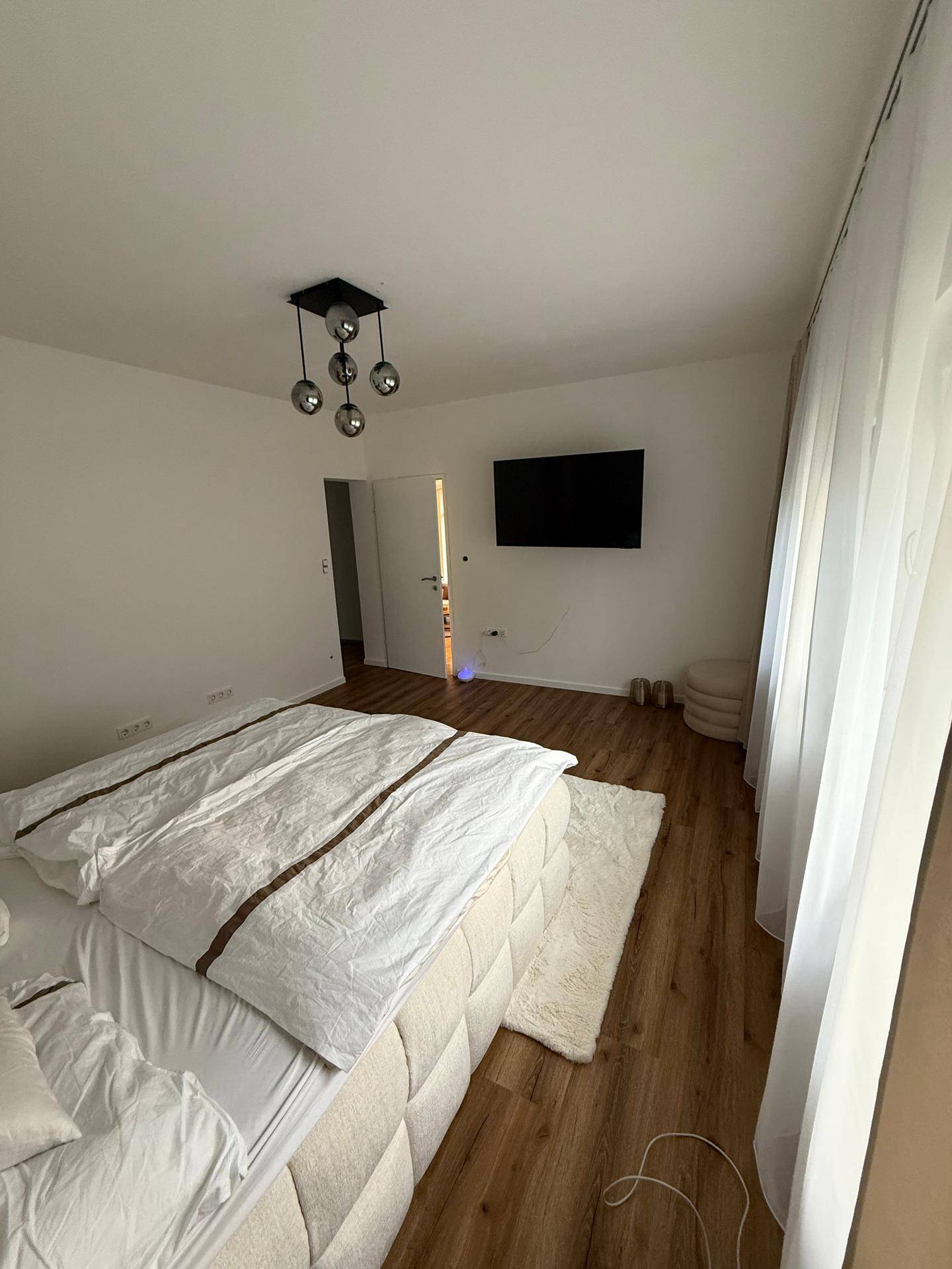 Komfortables Schlafzimmer mit hellem Holzboden und Zugang zu einem weiteren Raum.