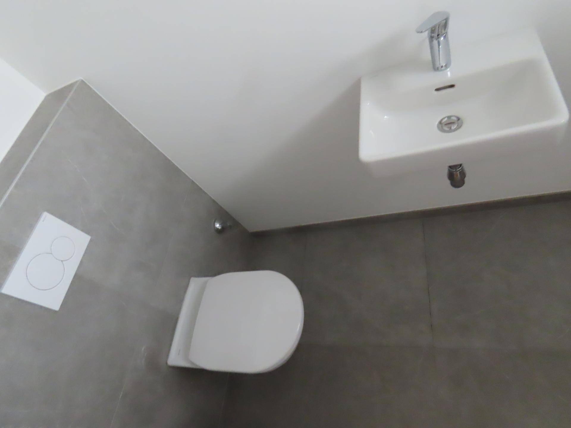 Modernes Gäste-WC mit wandhängender Toilette und kleinem Waschbecken.