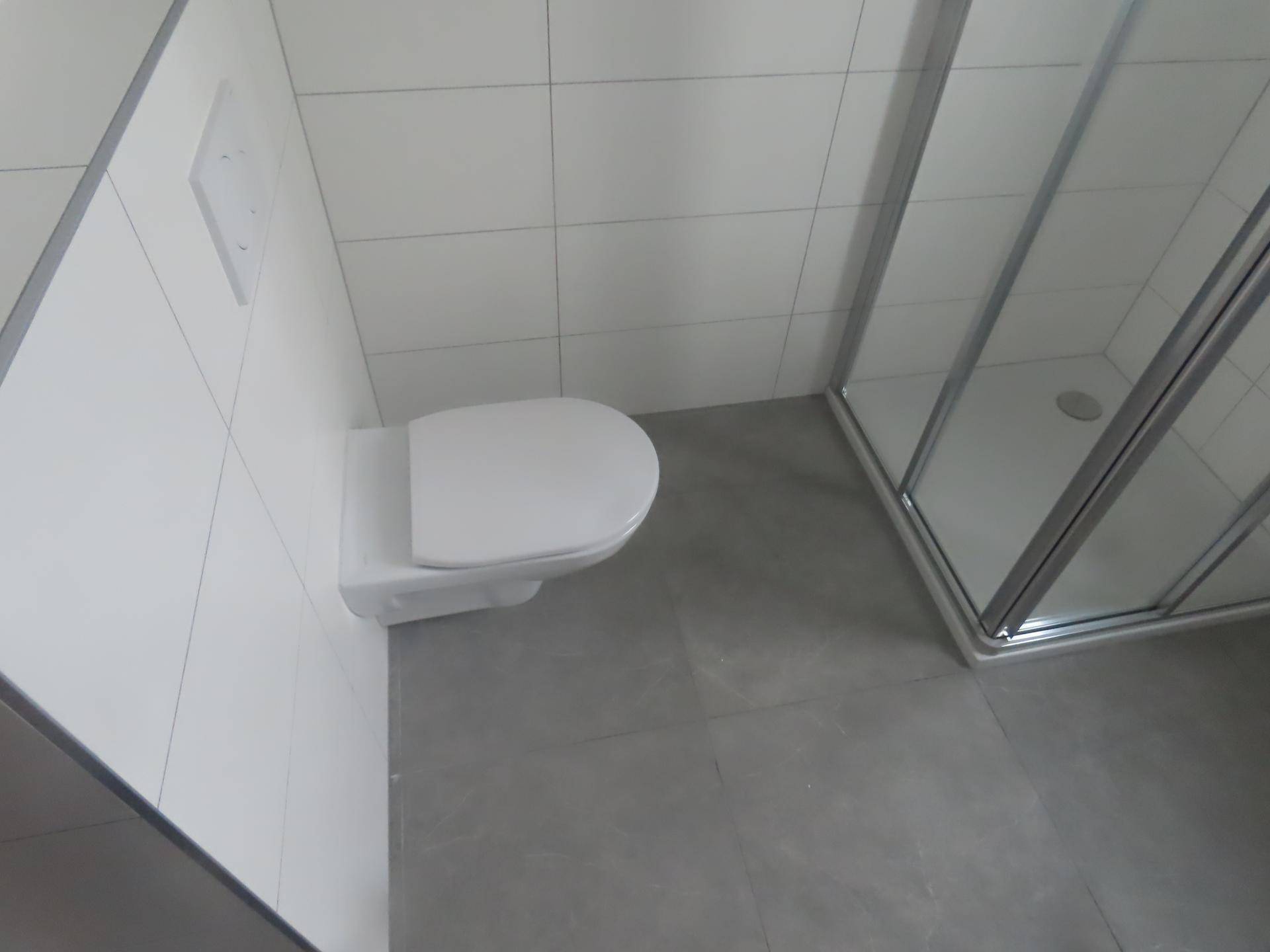 Modernes Badezimmer mit wandhängender Toilette und Duschkabine.