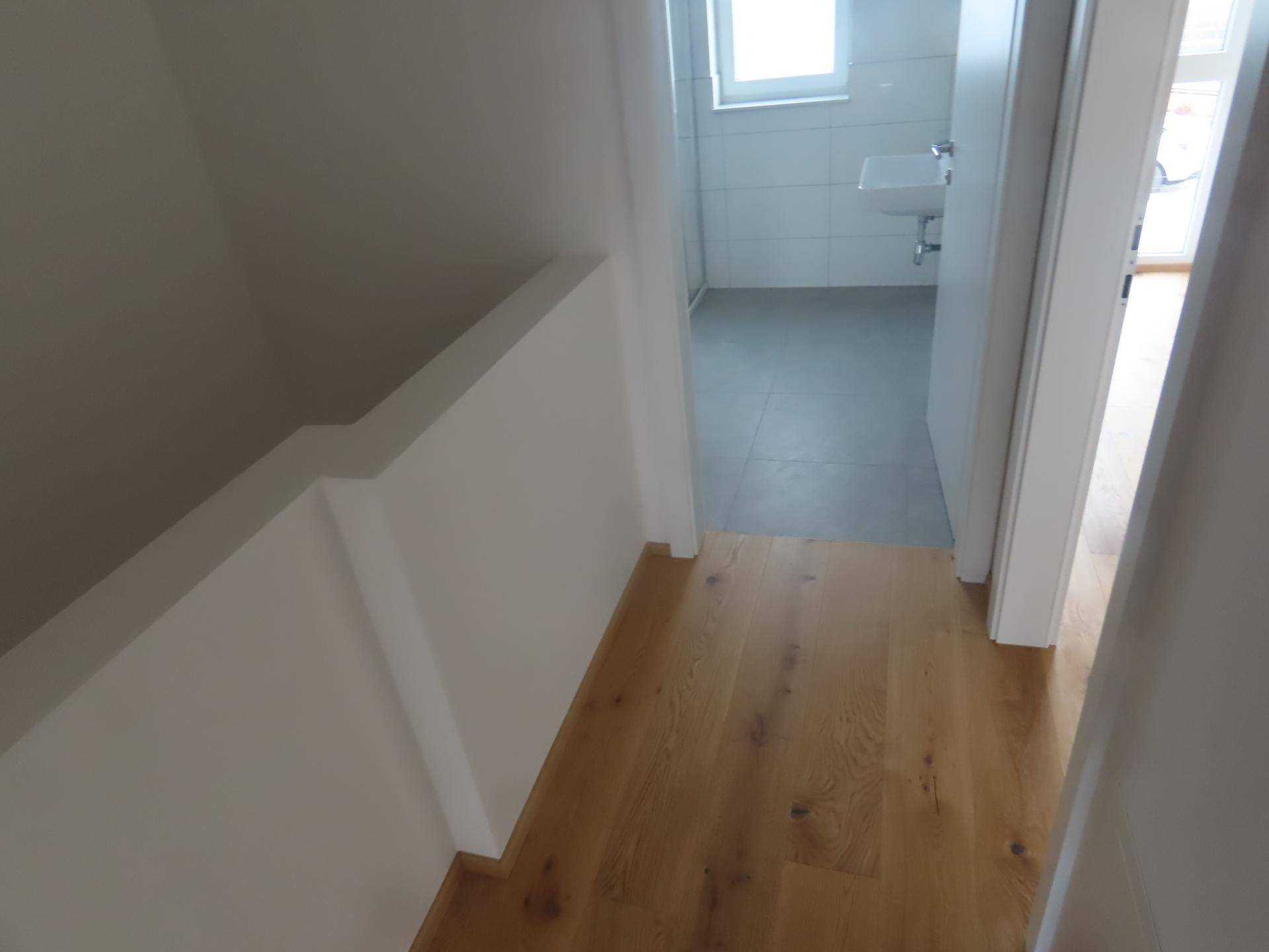 Flur mit Holzboden, der zu einem Badezimmer führt.