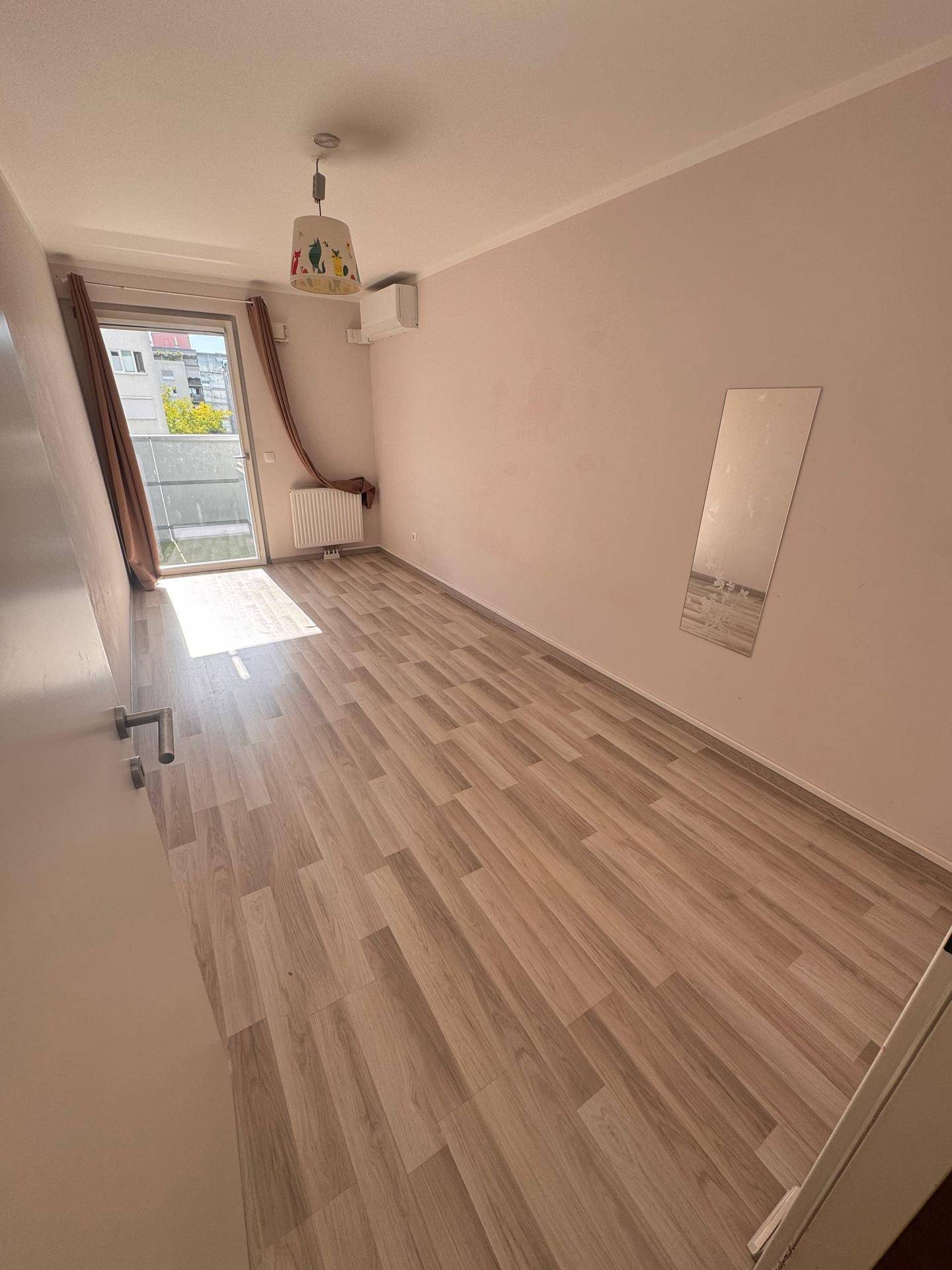 Freundliches Zimmer mit Laminatboden, Klimaanlage und direktem Zugang zum Balkon.