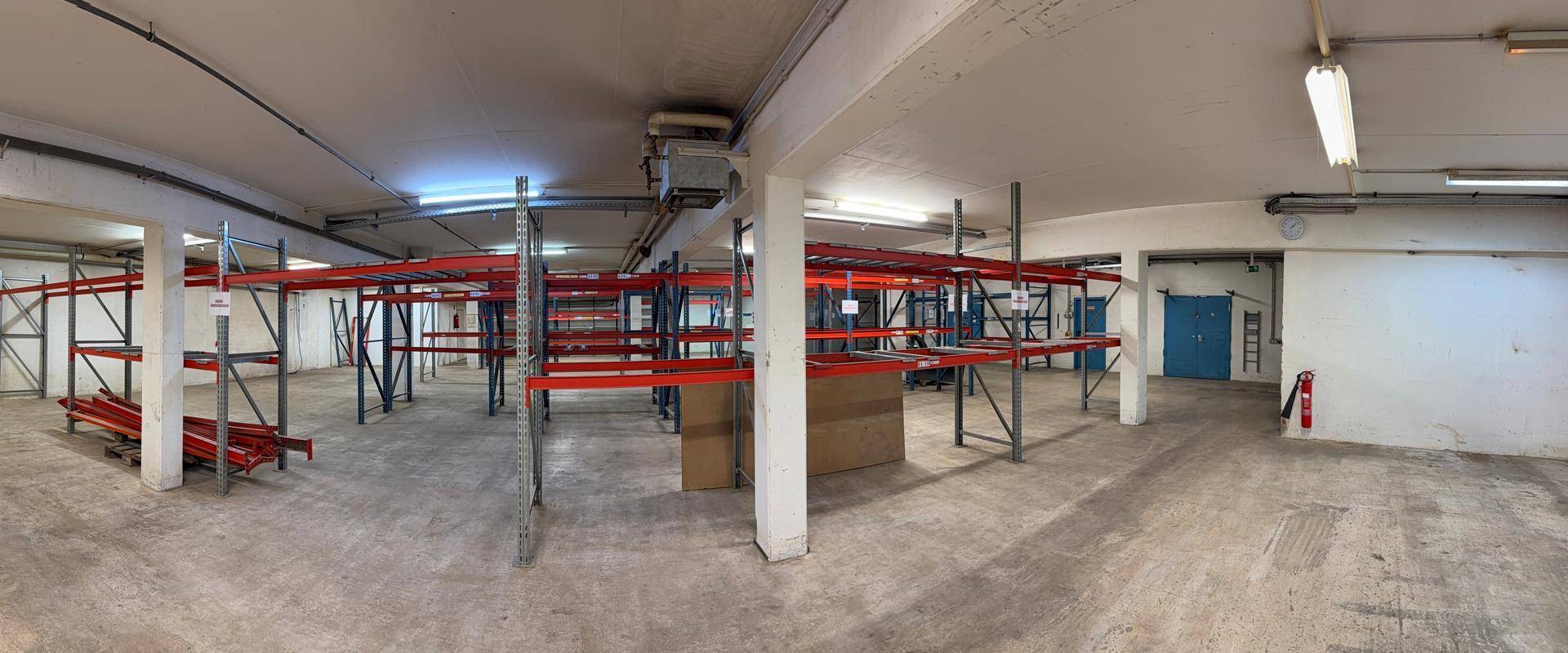 Großer Lagerraum mit Betonboden und leeren Regalsystemen, ideal für industrielle Nutzung.
