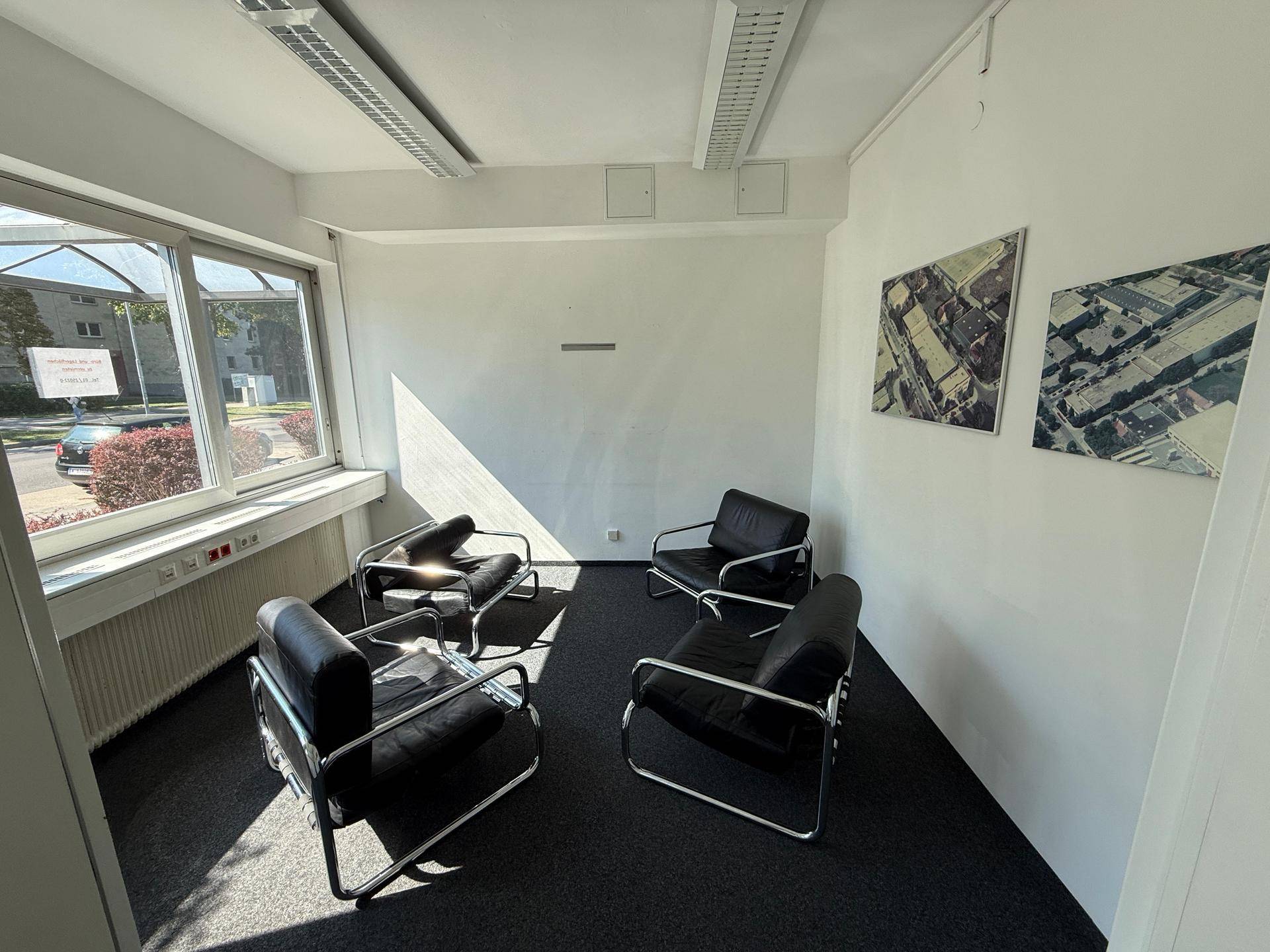 Wartebereich mit Teppichboden, modernen Sesseln und großen Fenstern für natürliches Licht.