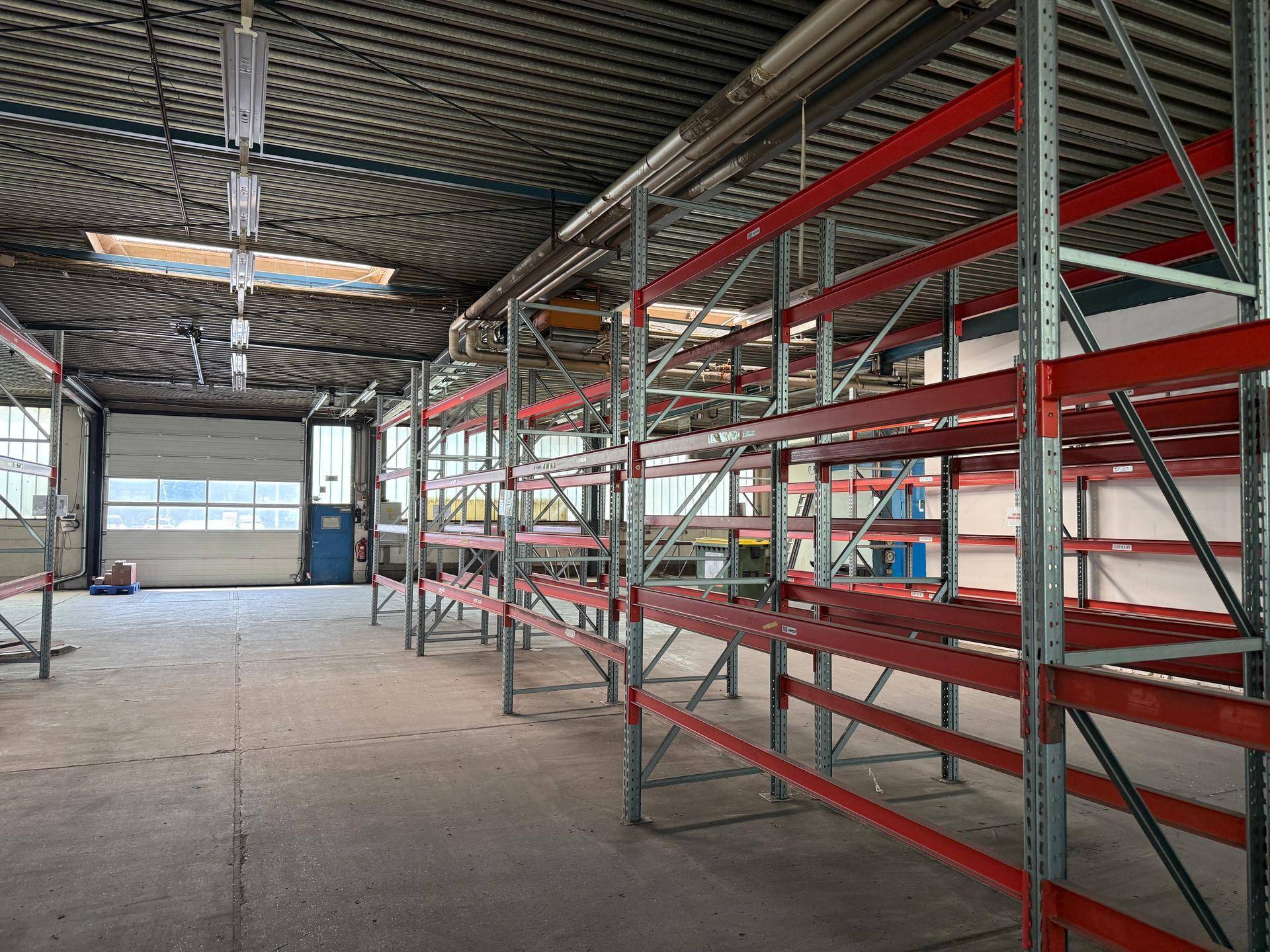 Lagerhalle mit Betonboden und hohen Regalsystemen, bereit für die effiziente Lagerung von Gütern.