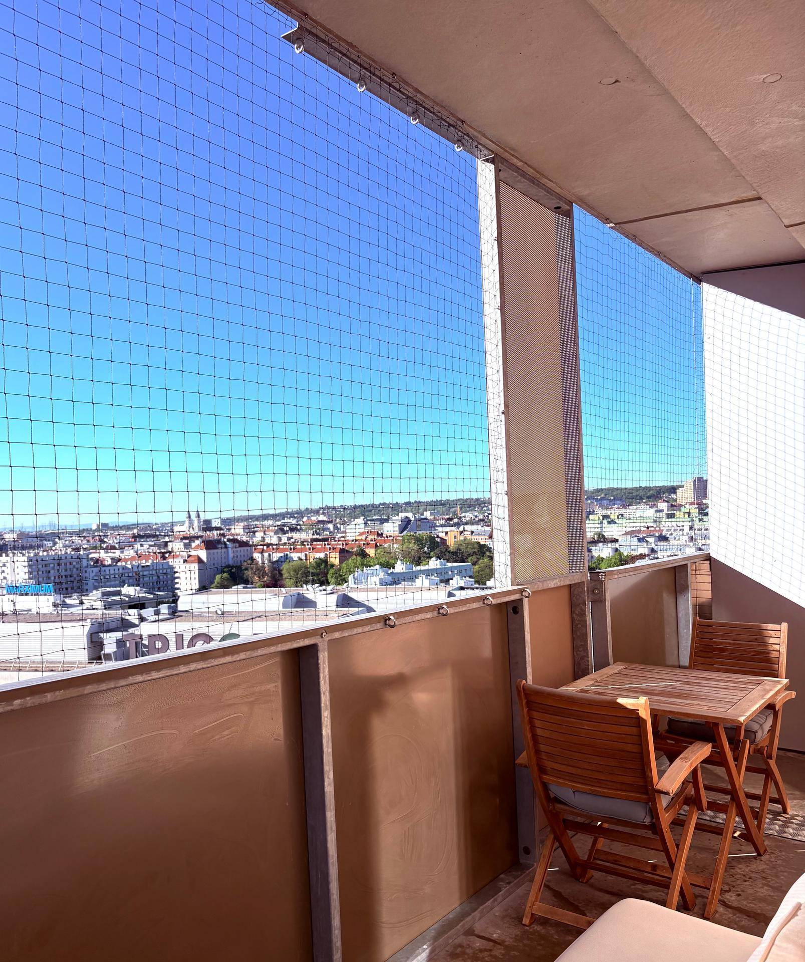 Balkon mit Holztisch und Stühlen, bietet einen weiten Blick über die Stadt.