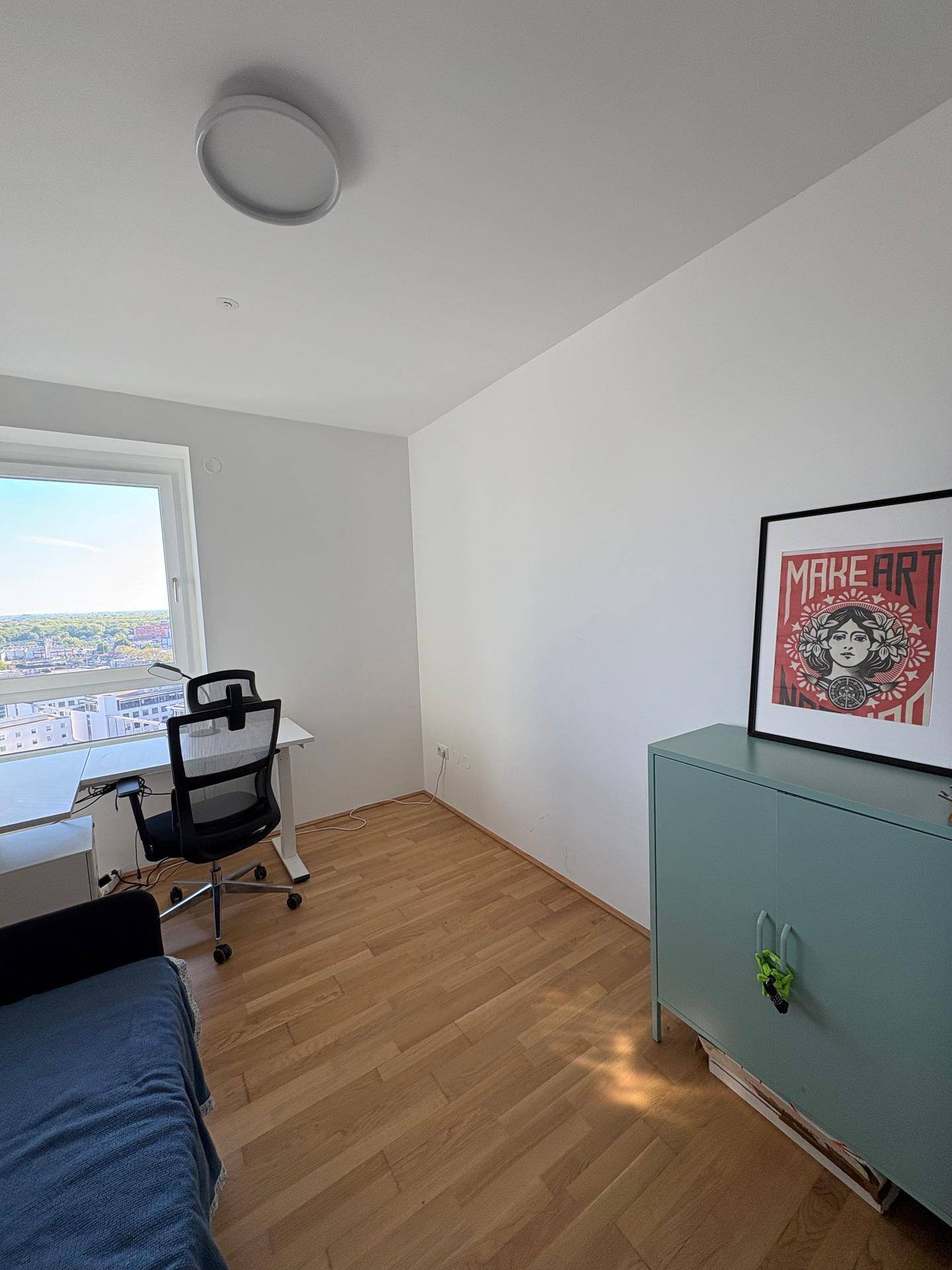 Helles Arbeitszimmer mit Schreibtisch, Bürostuhl und Blick auf die Stadt.