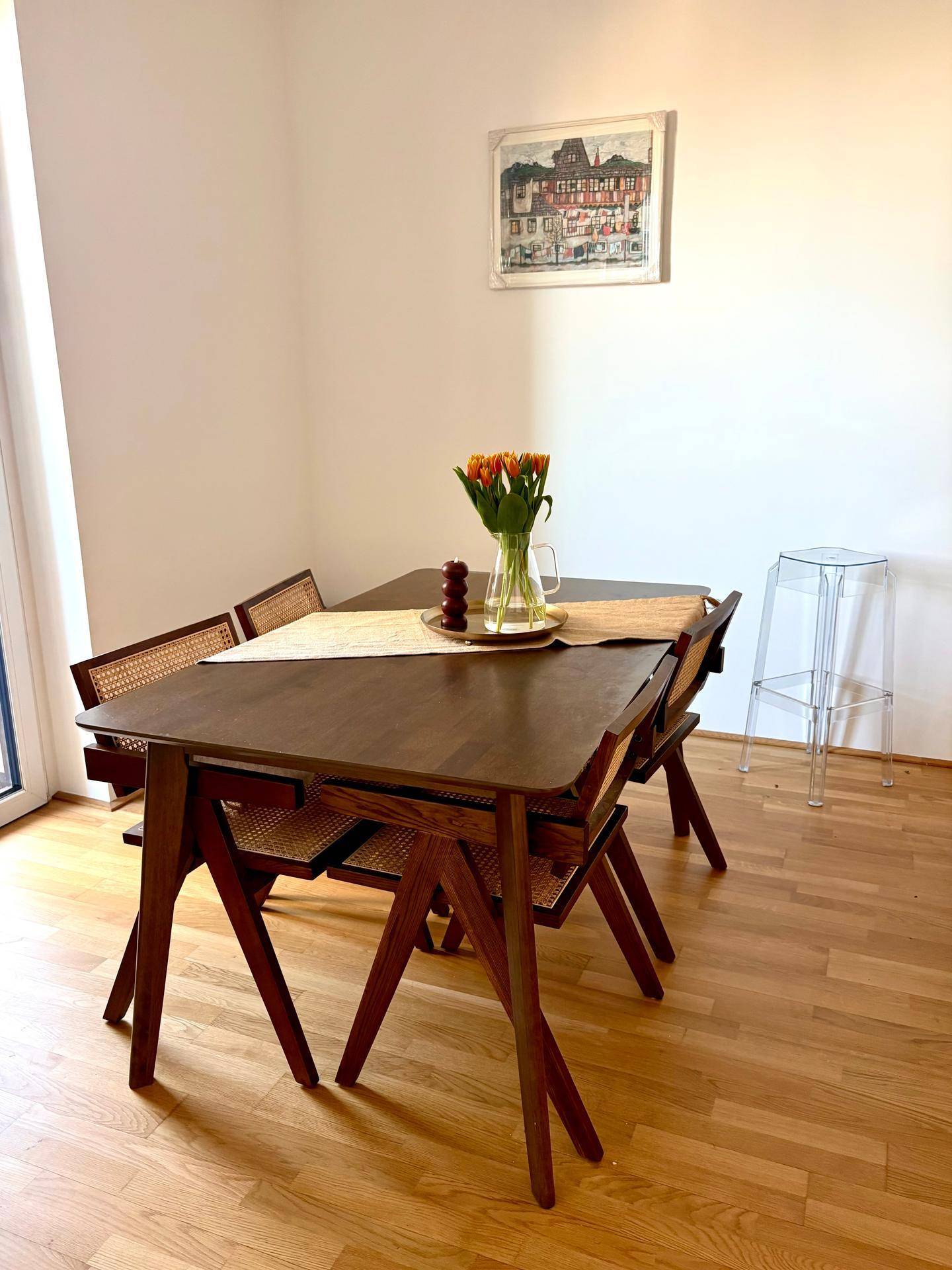Essbereich mit Holztisch und Stühlen, Holzboden und heller Wandgestaltung.