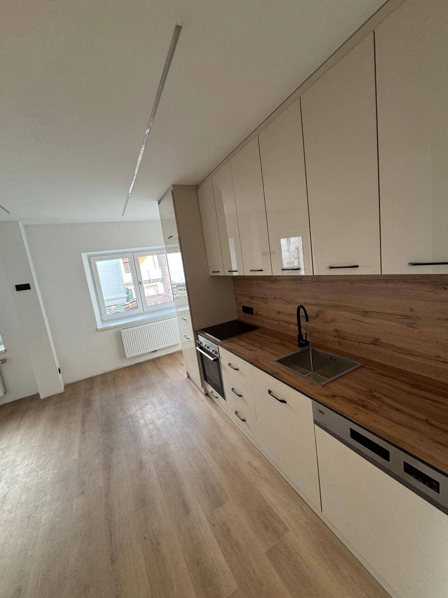 Moderne Küchenzeile mit Spüle, Geschirrspüler und Holzdetails in einem hellen, neuwertigen Zustand.