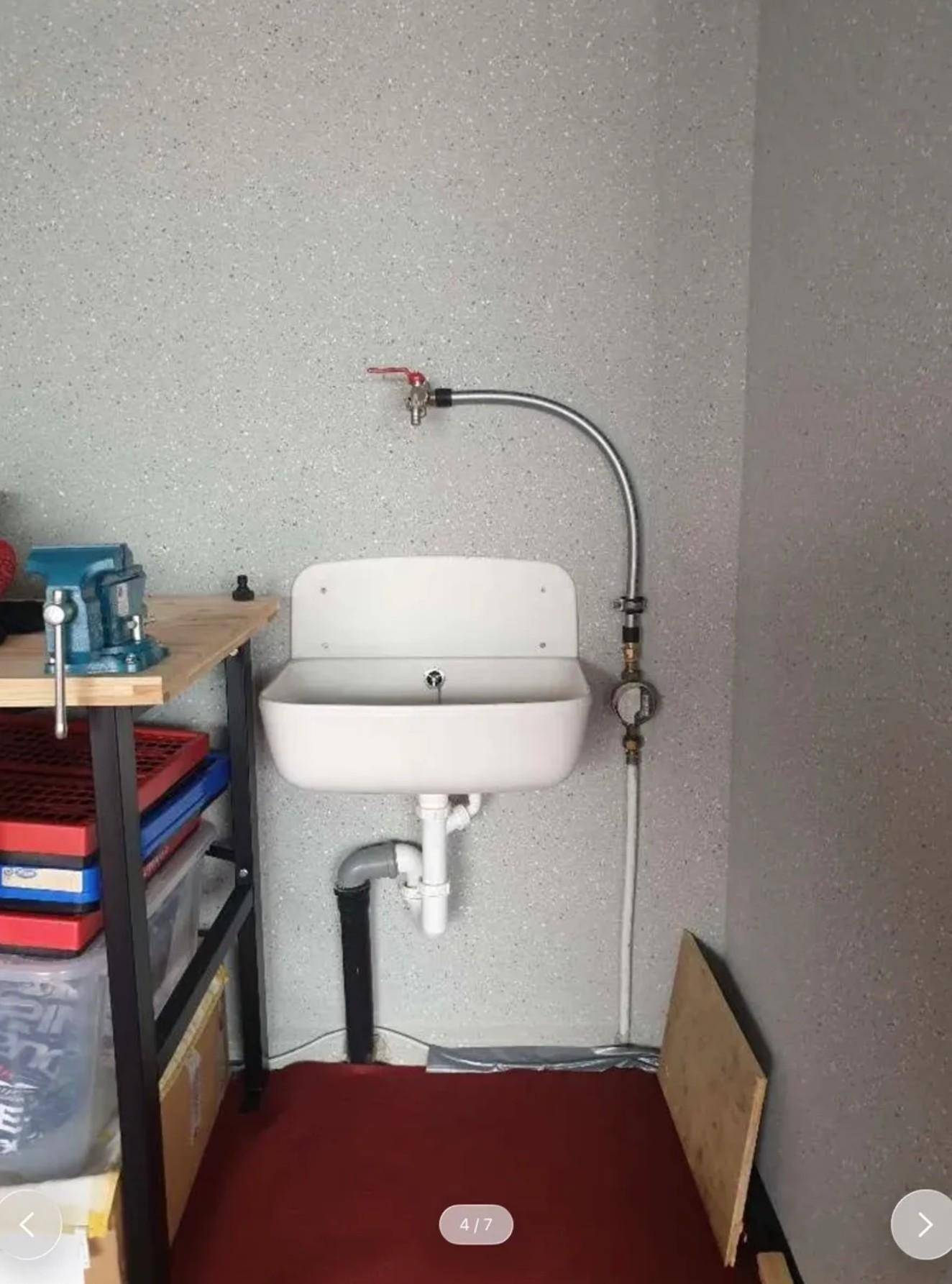 Detailansicht eines Waschbeckens mit Wasseranschluss in einem funktionalen Werkstattbereich.