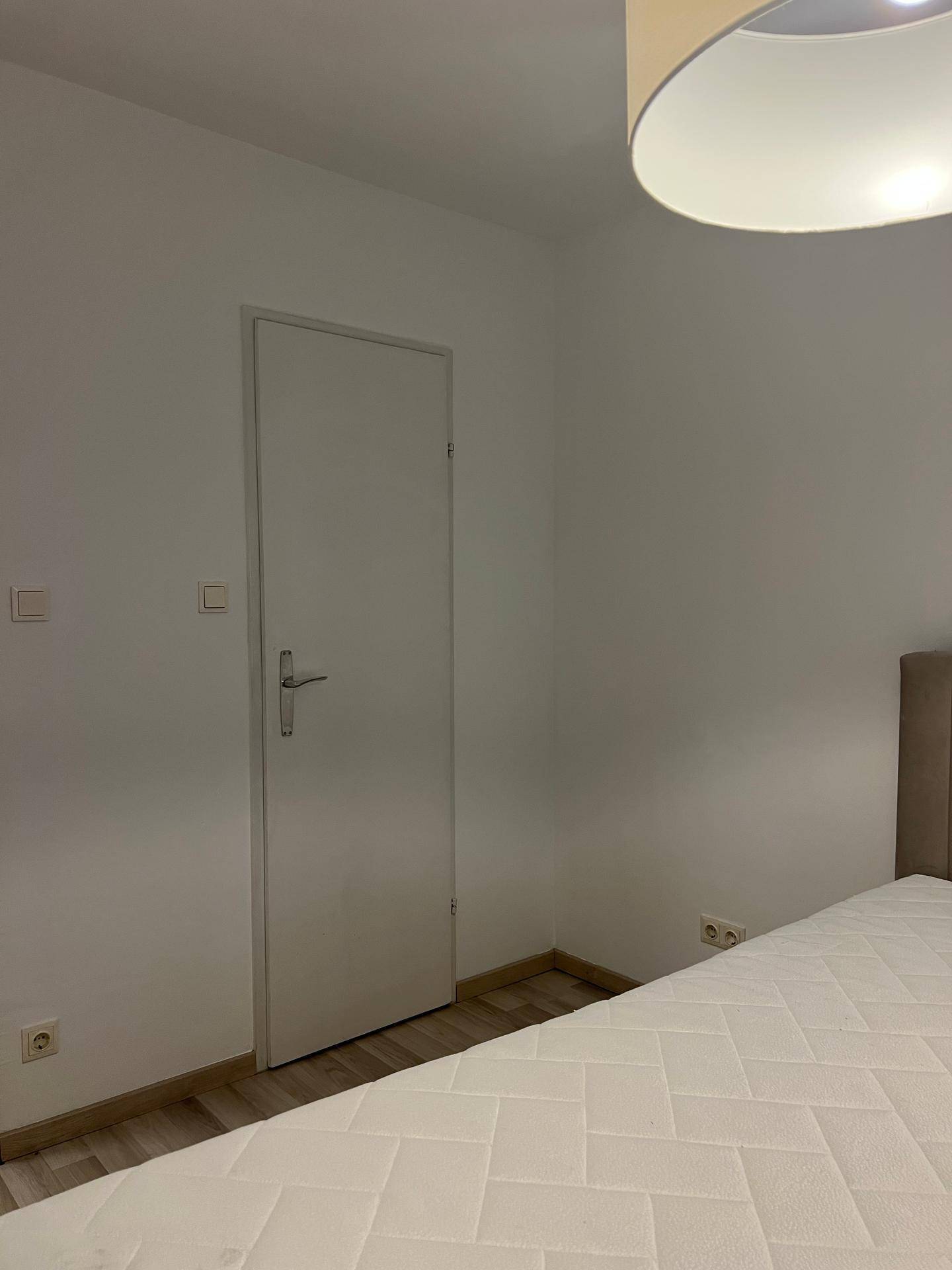 Schlafzimmer mit einer Tür und einem Teil des Bettes, das eine ruhige Atmosphäre schafft.
