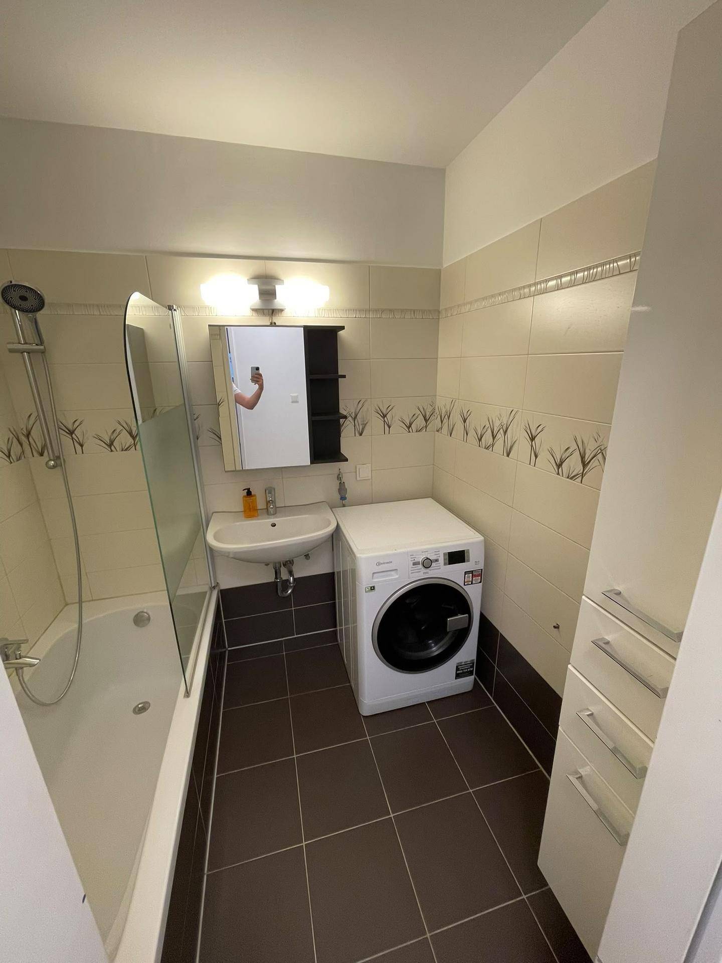 Funktionales Badezimmer mit Badewanne, Dusche, Waschbecken und integrierter Waschmaschine.