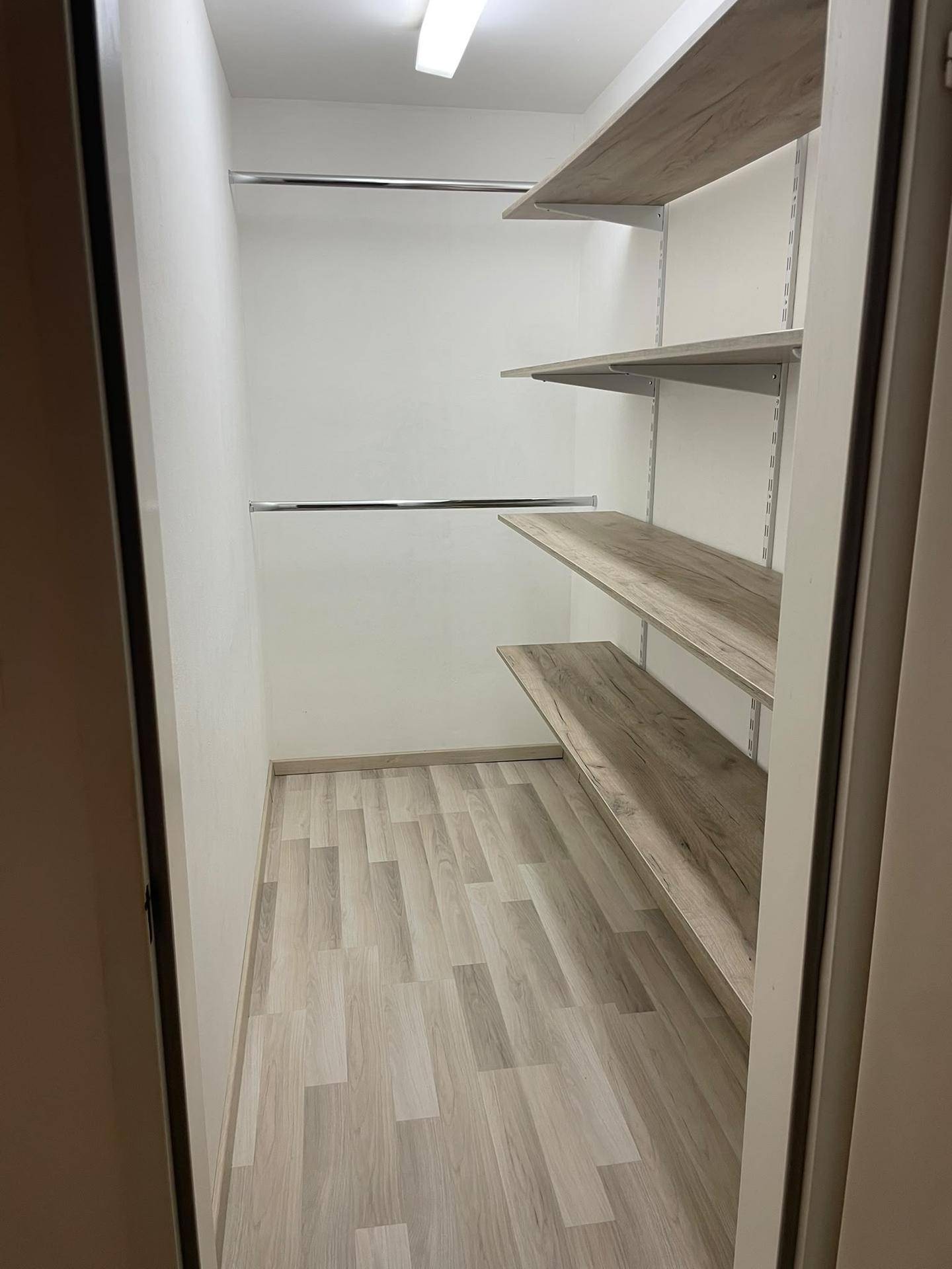 Praktischer begehbarer Kleiderschrank mit Regalen und Kleiderstangen für optimale Organisation.