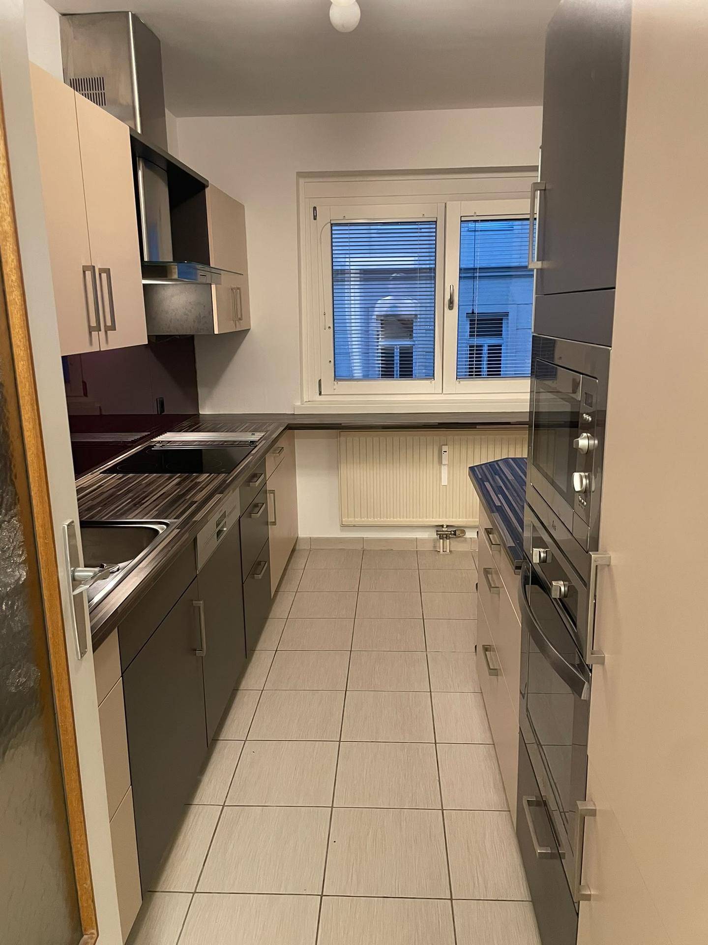 Gut ausgestattete Küche mit Fenster, Einbauofen und Mikrowelle für komfortables Kochen.