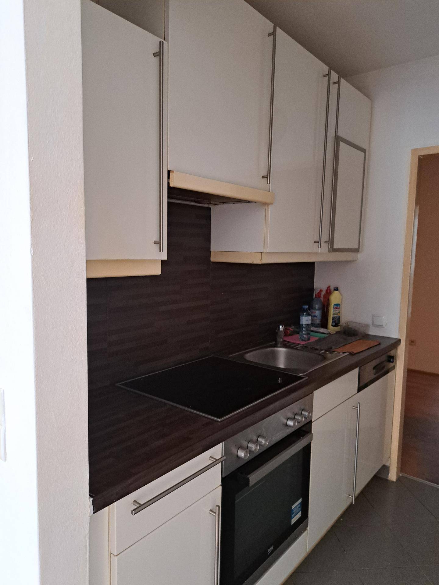 Funktionale Küche mit weißen Schränken, dunkler Arbeitsplatte und integrierten Einbaugeräten.