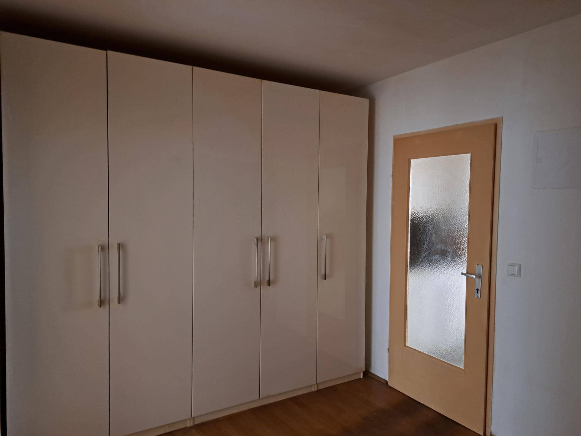 Großer Kleiderschrank mit hellen Fronten und einer Tür mit Milchglas, passend zum Interieur.