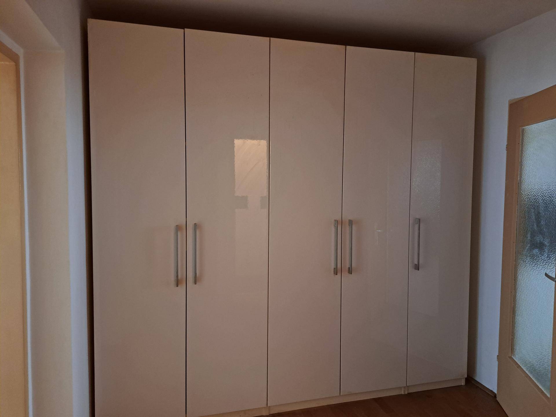 Großer, moderner Kleiderschrank mit glänzenden Türen und silbernen Griffen, gut erhalten.