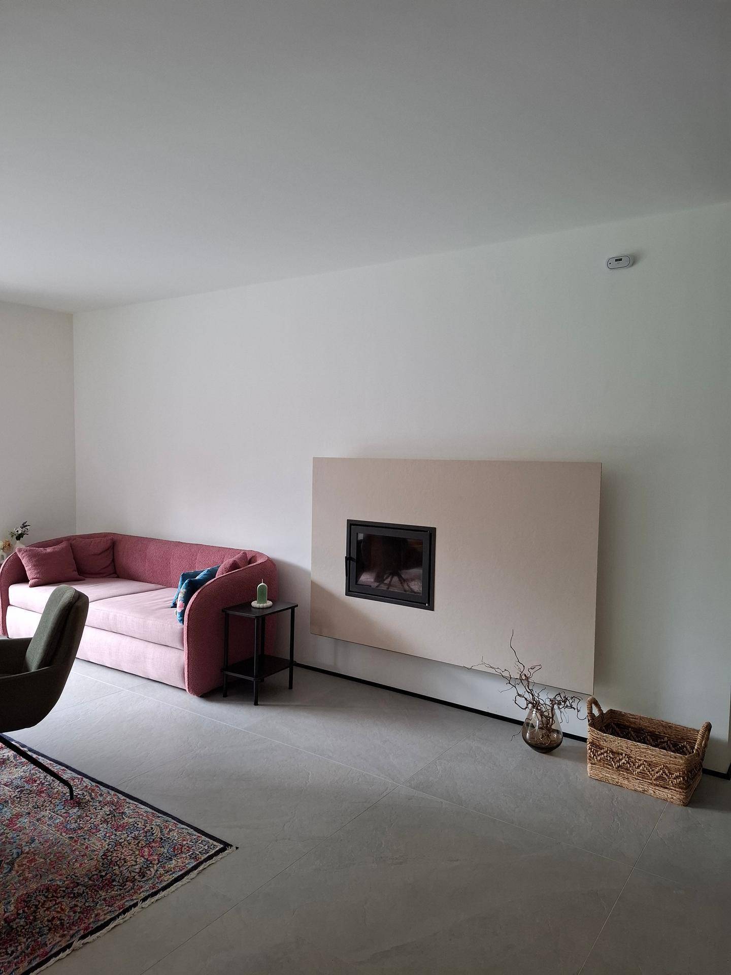 Gemütliches Wohnzimmer mit rosa Sofa, modernem Kamin und hellen Fliesenboden.