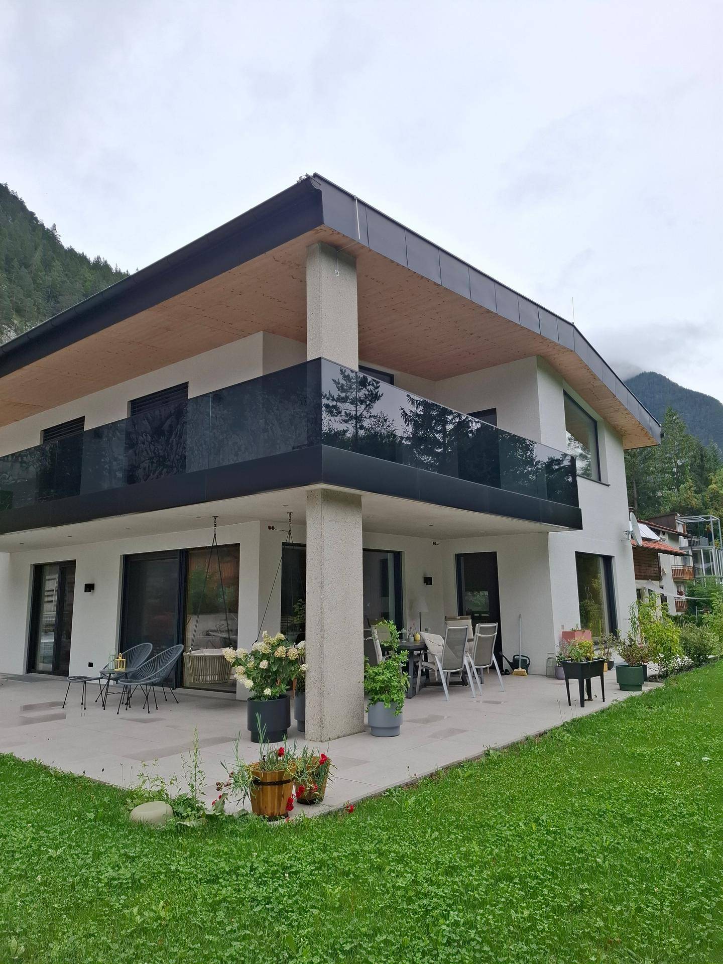 Große, möblierte Terrasse mit Rasenfläche und Blick auf die umliegende Berglandschaft.