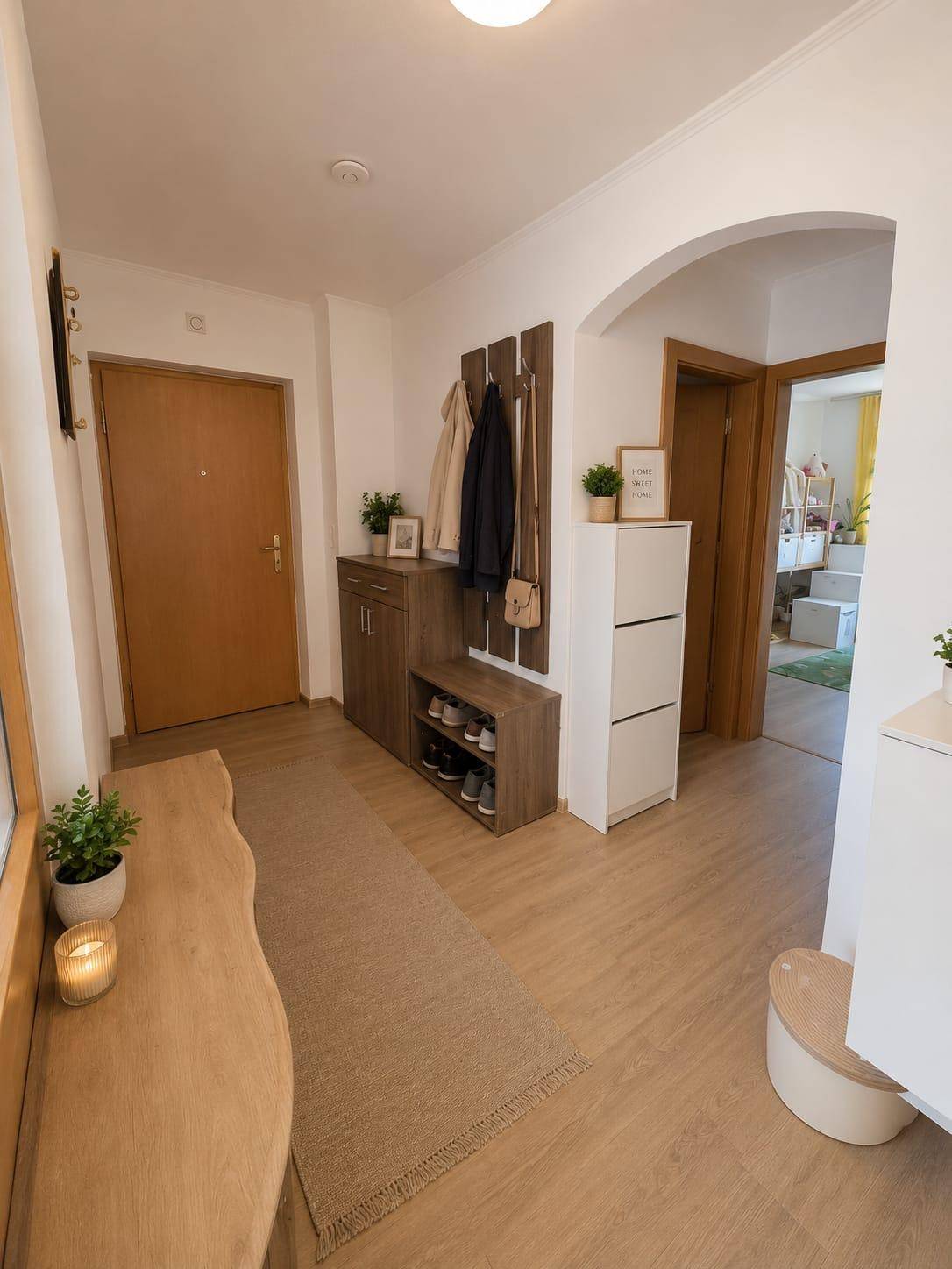 Heller Eingangsbereich mit Garderobe, Schuhschrank und Holzboden.