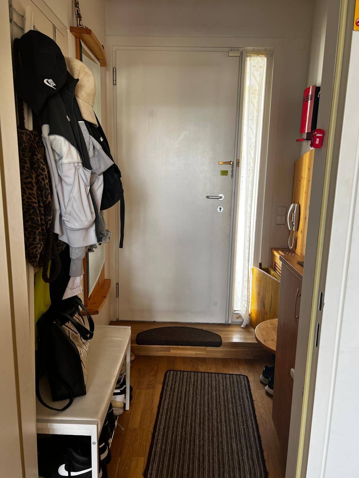 Eingangsbereich mit Haustür, Garderobe und Schuhablage, ausgestattet mit Holzfußboden.
