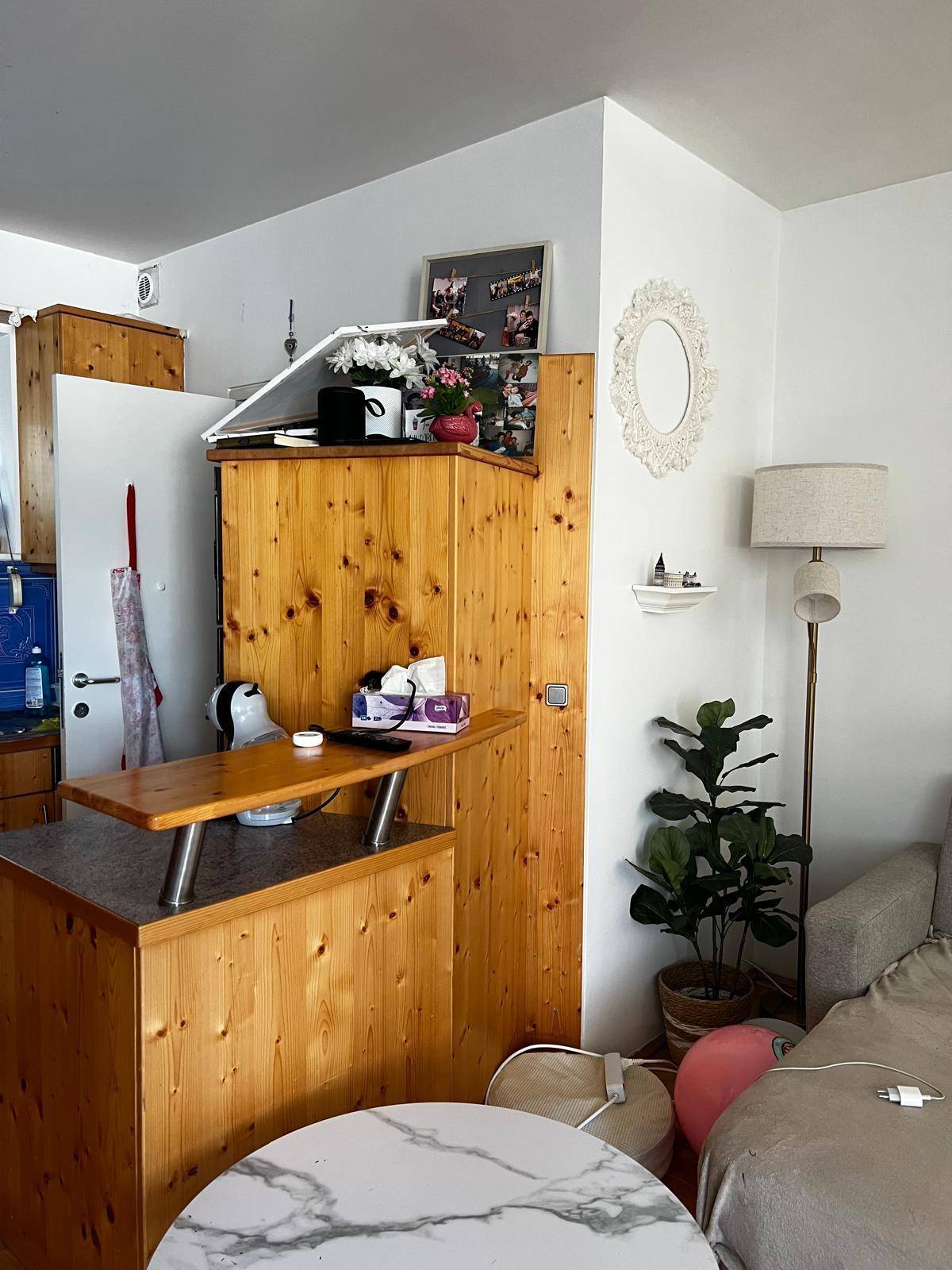 Offener Küchenbereich mit Holzschränken und einer kleinen Theke, angrenzend an den Wohnbereich.
