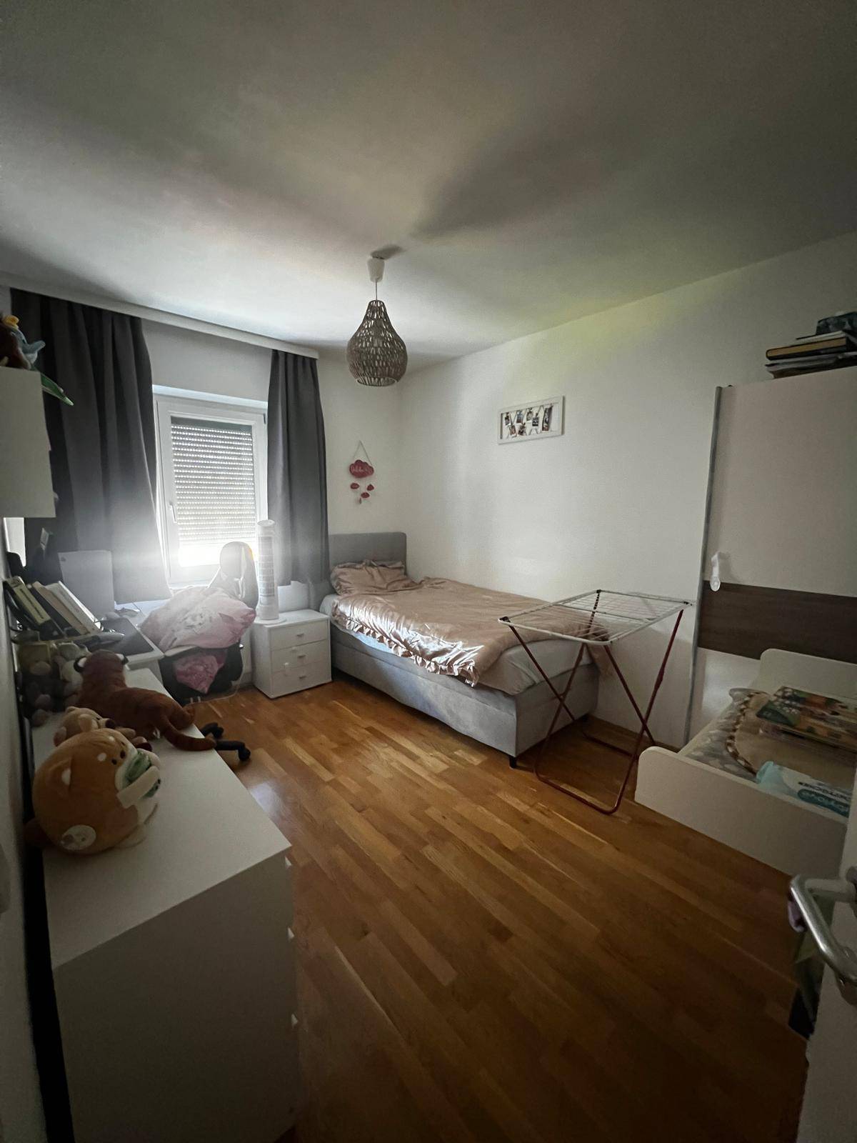 Kinderzimmer mit einem Bett, einem kleinen Beistellbett und einem Fenster für Tageslicht.