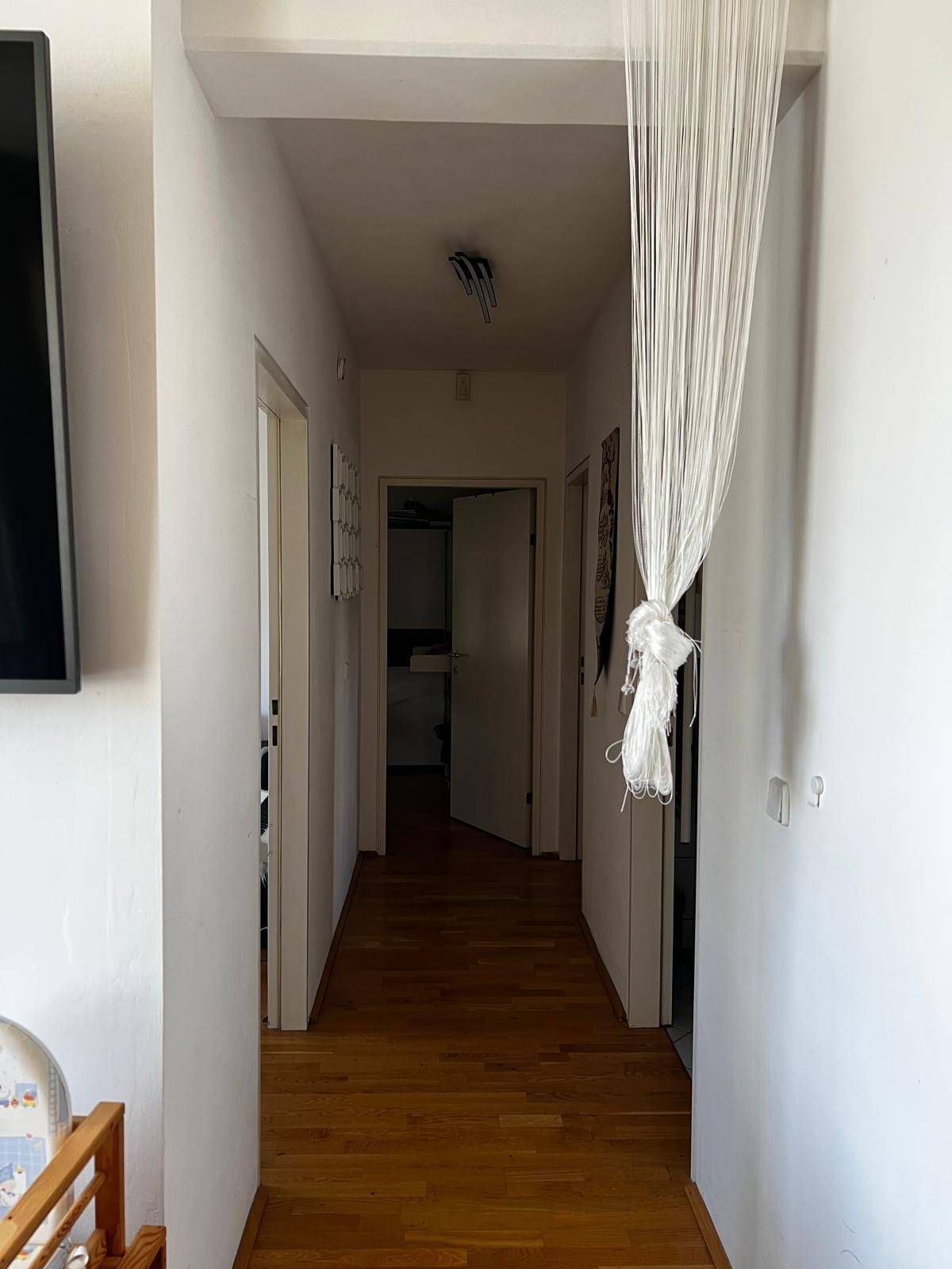 Langer, heller Flur mit Holzfußboden, der zu den verschiedenen Zimmern der Wohnung führt.