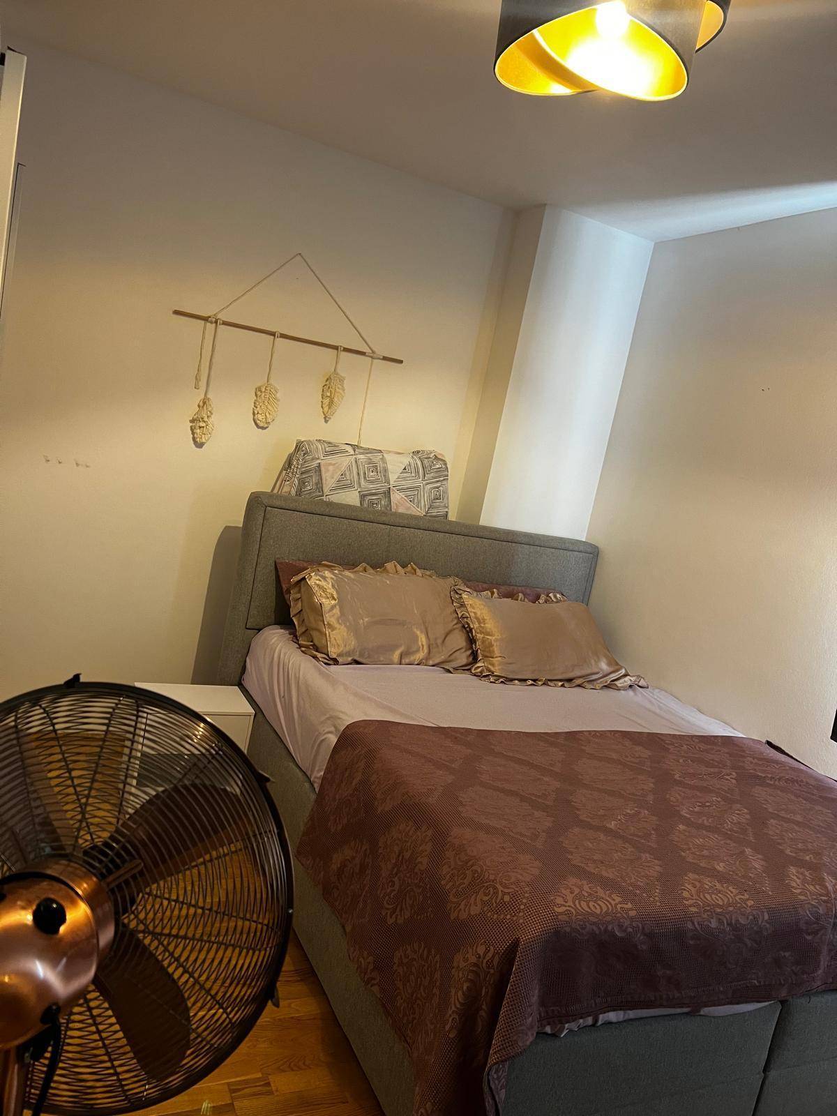Gemütliches Schlafzimmer mit einem bequemen Bett und einem Ventilator für angenehme Temperaturen.