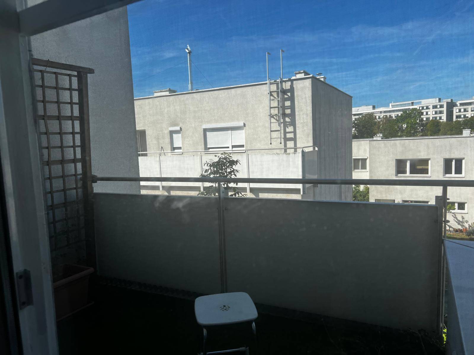 Balkon mit Blick auf umliegende Gebäude und einem kleinen Hocker.