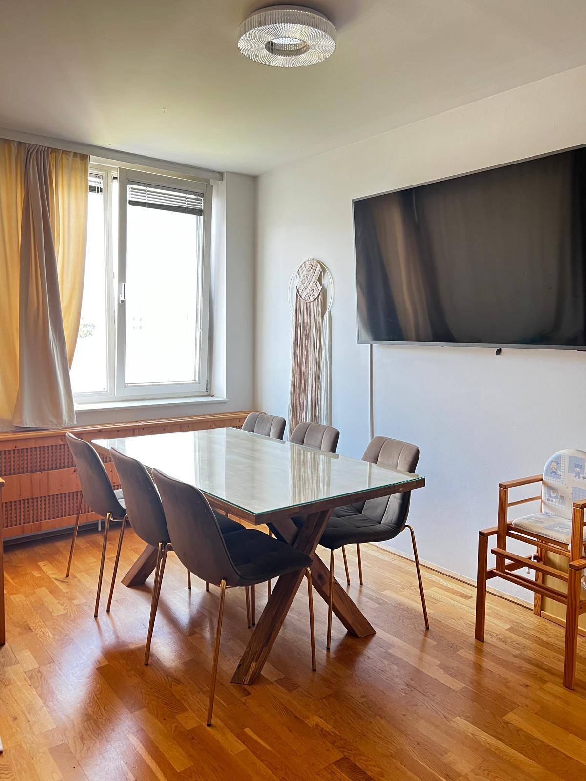 Essbereich mit großem Holztisch, modernen Stühlen und einem an der Wand montierten Fernseher.