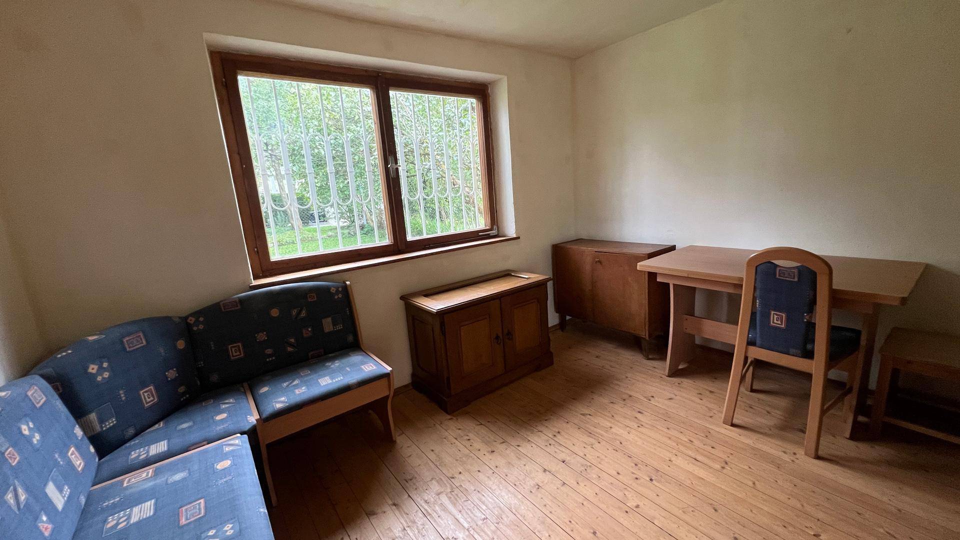 Helles Zimmer mit Holzboden, bequemen Sofa und weitem Blick ins Grüne.