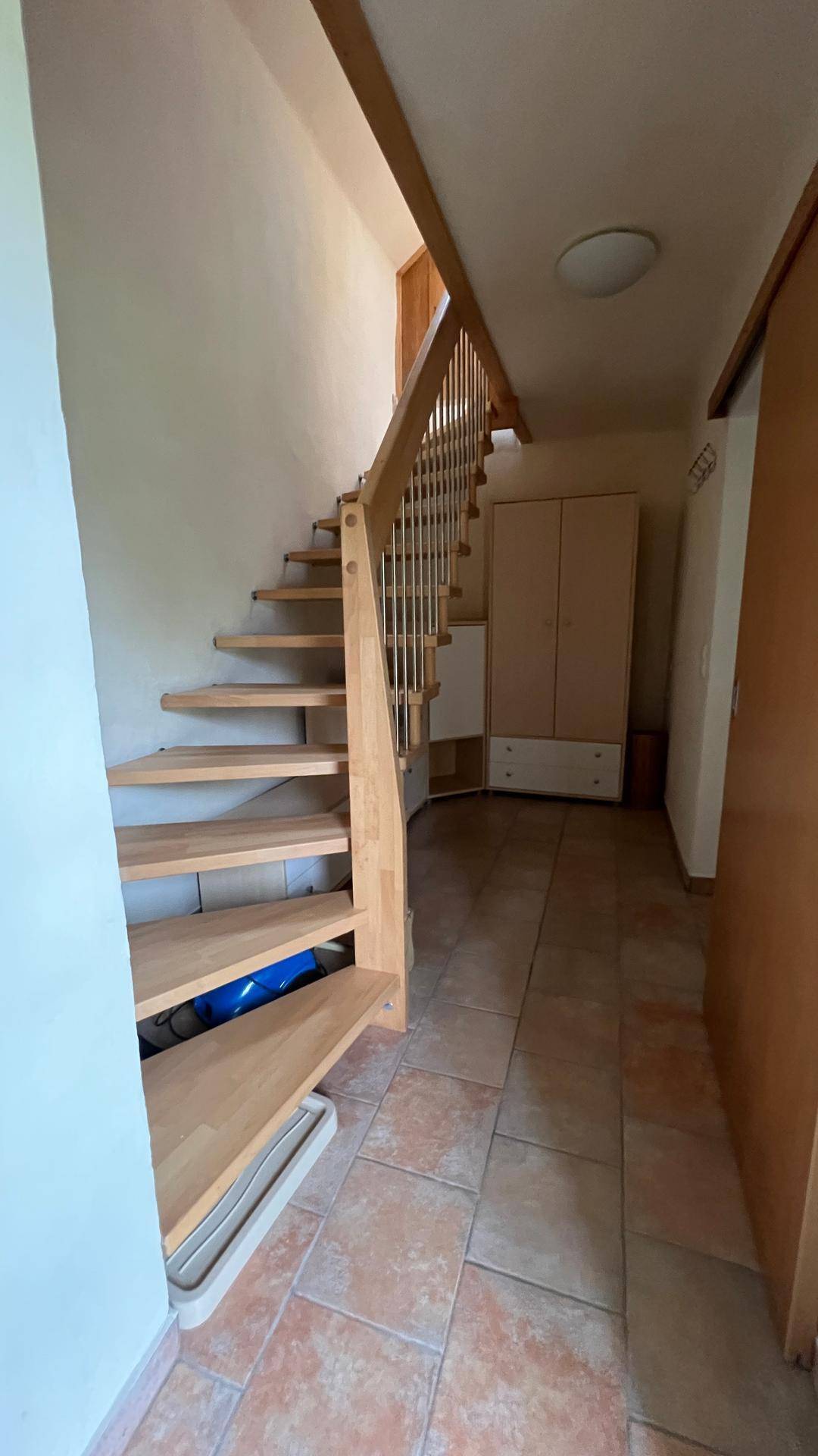 Heller Flur mit Holztreppe und Fliesenboden, der die Etagen verbindet.