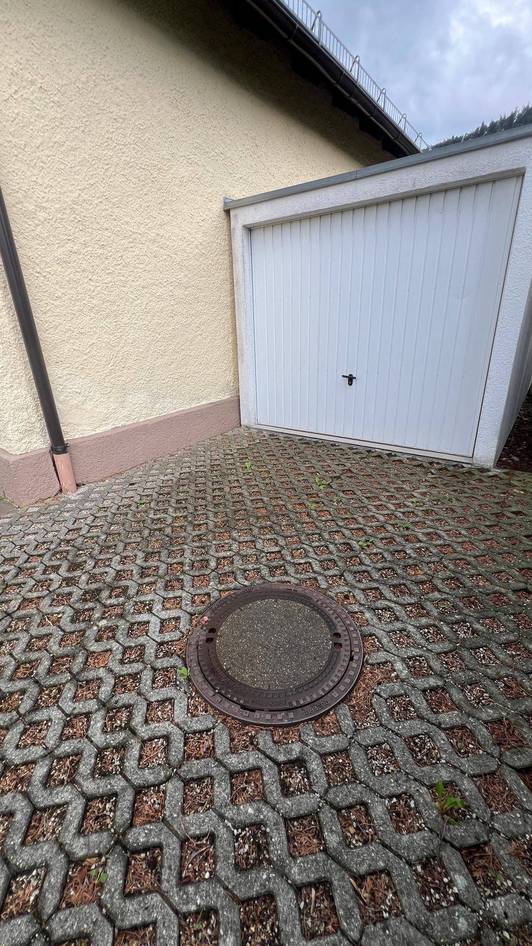 Einzelgarage mit gepflasterter Zufahrt und einem robusten, weißen Garagentor.
