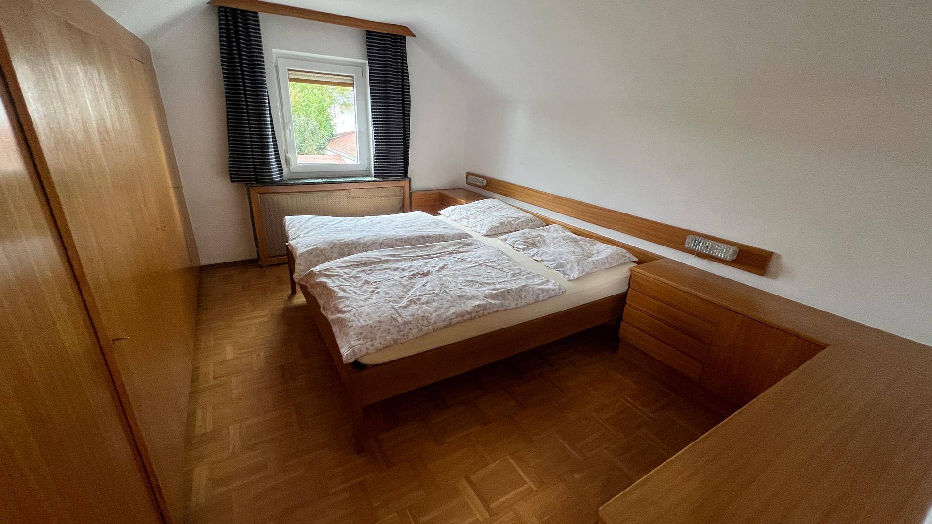 Gemütliches Schlafzimmer mit Holzboden, Doppelbett und charakteristischer Dachschräge.